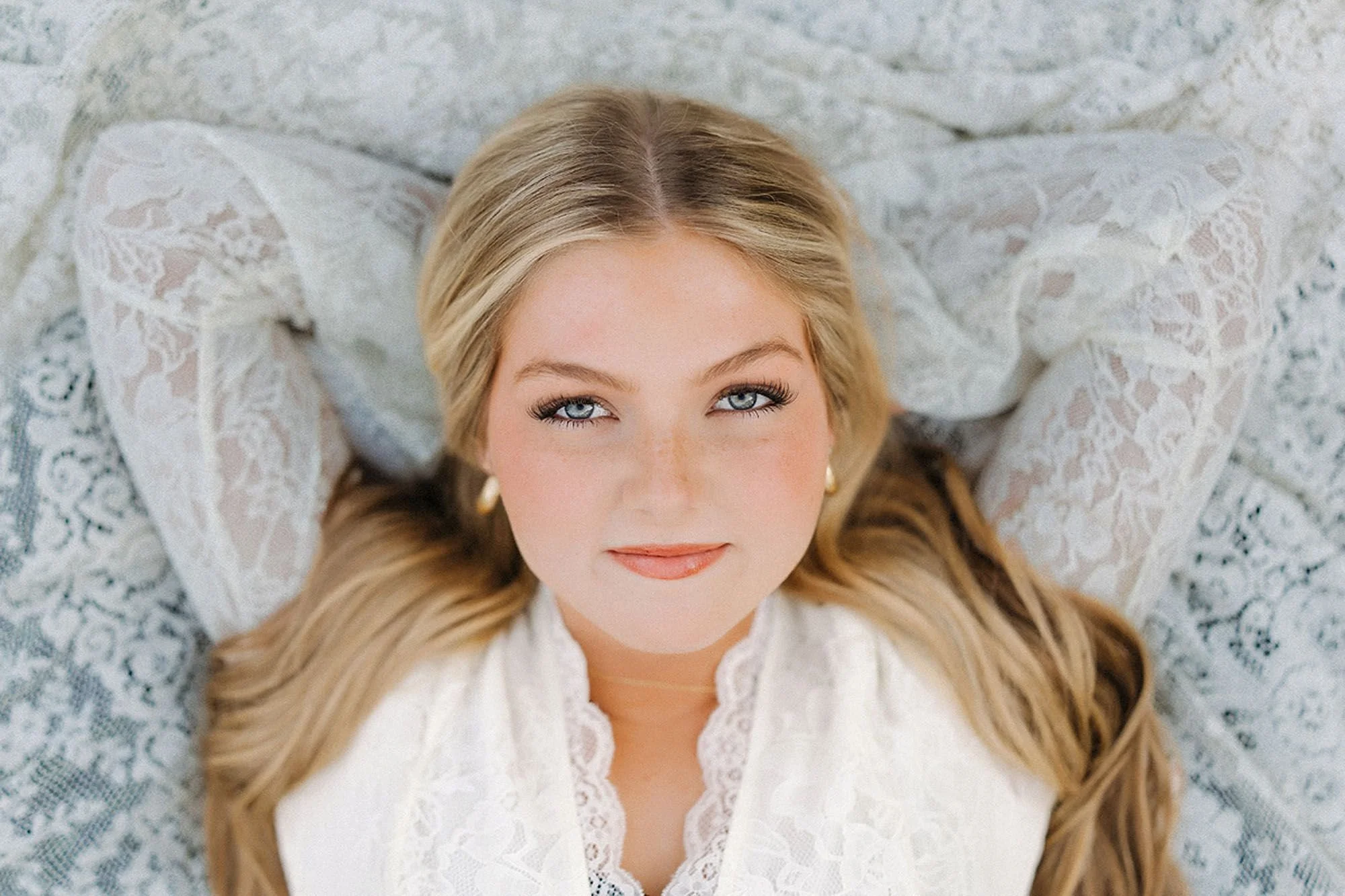 Natural senior photos highlighting a blonde graduate in a delicate lace top, creating a bright, classic, and unforgettable senior portrait