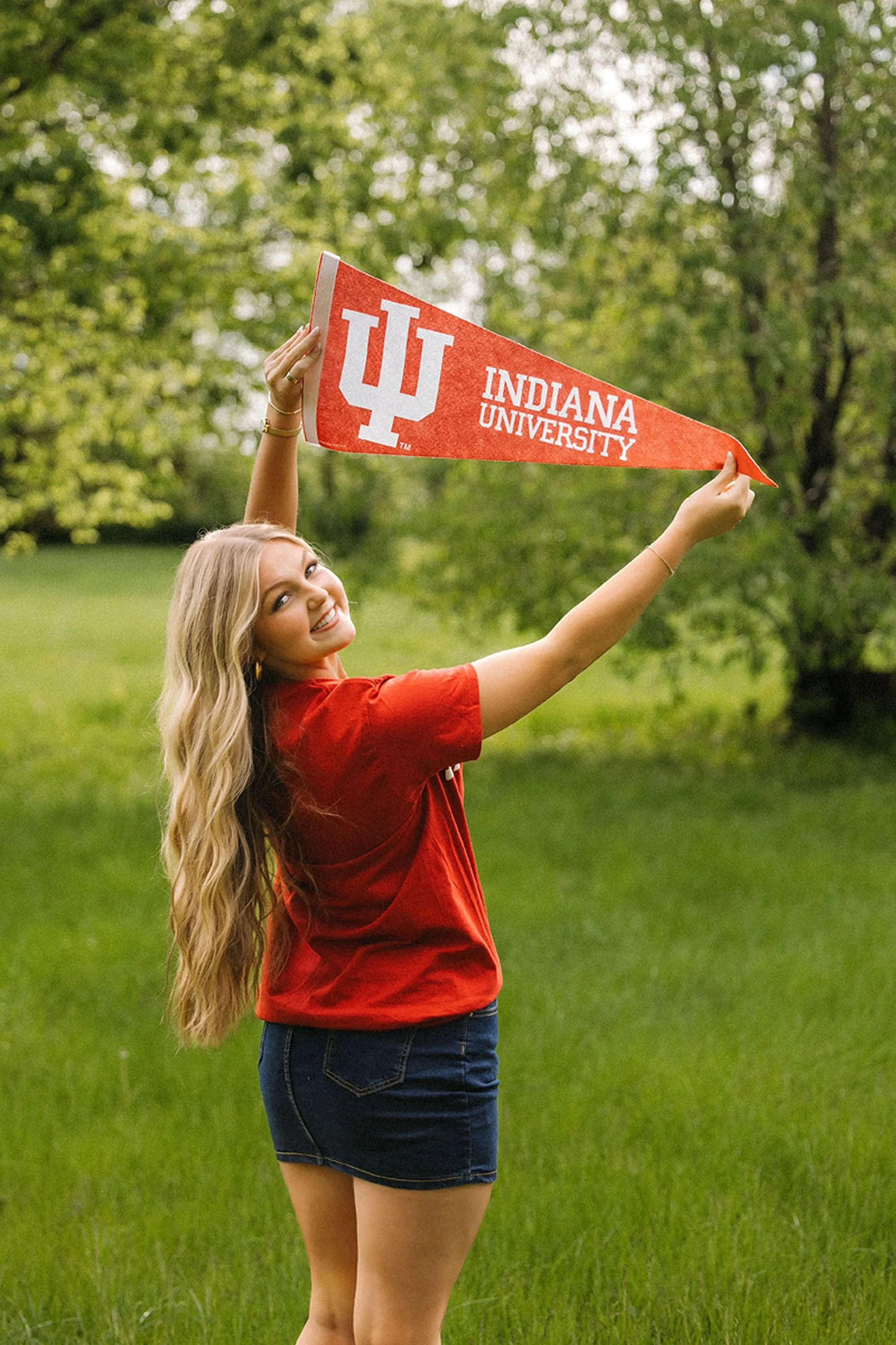 Hamilton Heights Senior Photos showcasing a future Indiana University student celebrating graduation with a vibrant college pennant surrounded by beautiful greenery