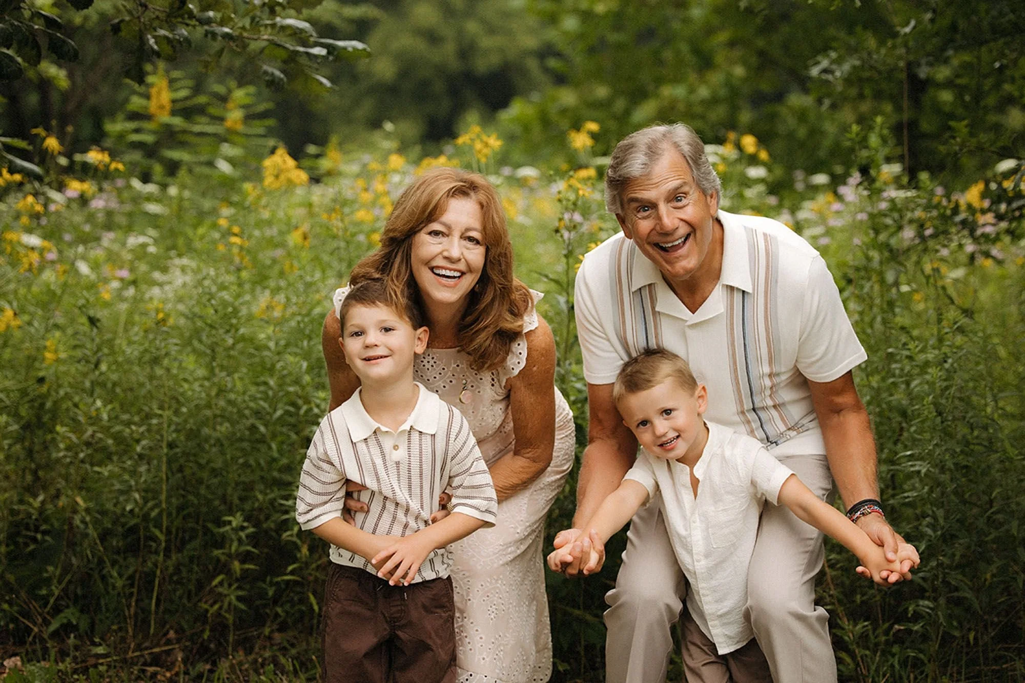 Grandparents kneeling in a wildflower field with their young grandsons during a family photo session in Westfield, Indiana.
