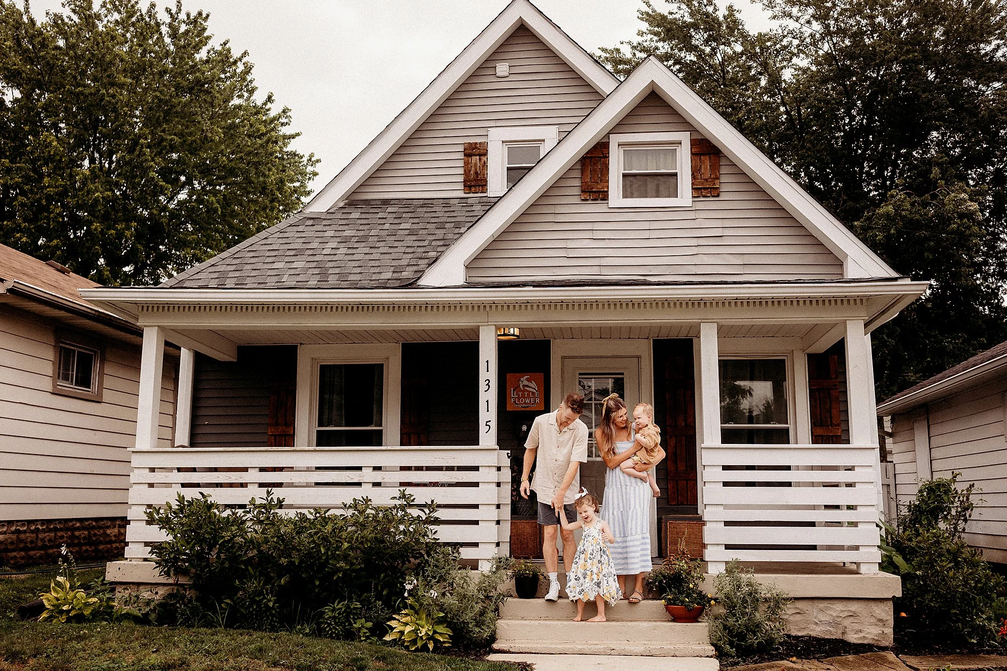 A family smiles for a photo in front of their house in Indianapolis, Indiana, taken during a photography session