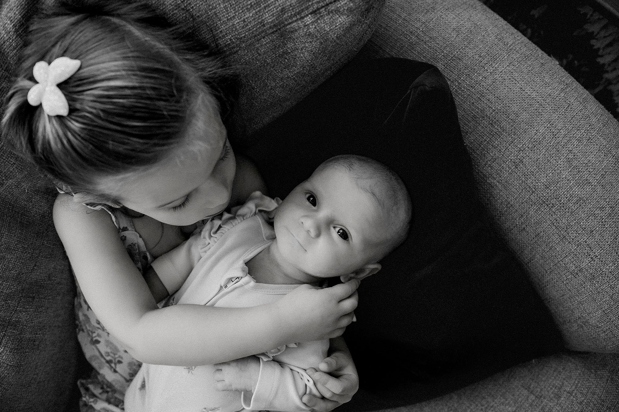 toddler sibling holding newborn baby during lifestyle photography session
