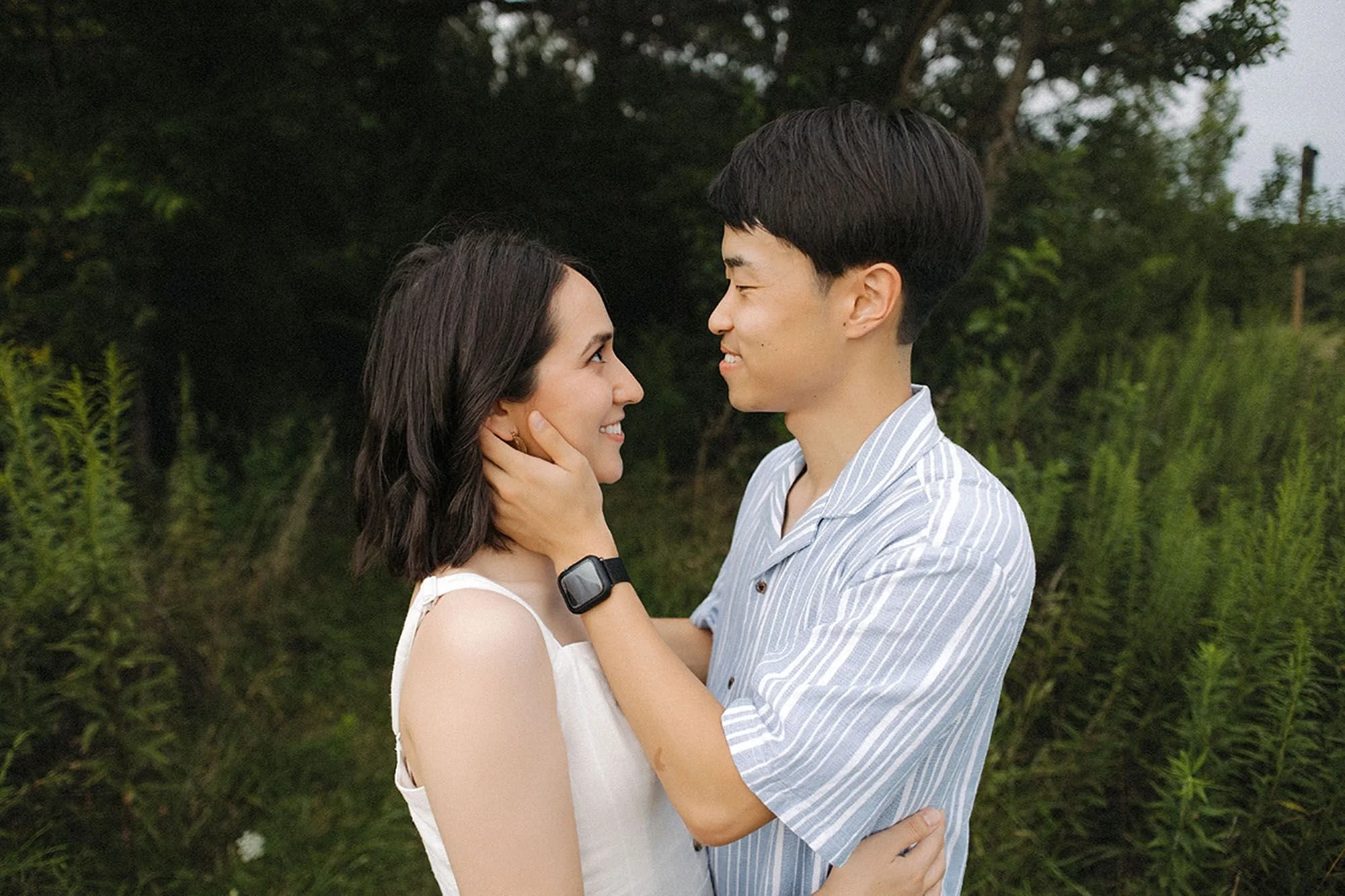 Young couple smiling and embracing face-to-face in a green field during a Flat Fork Creek Park family photo session