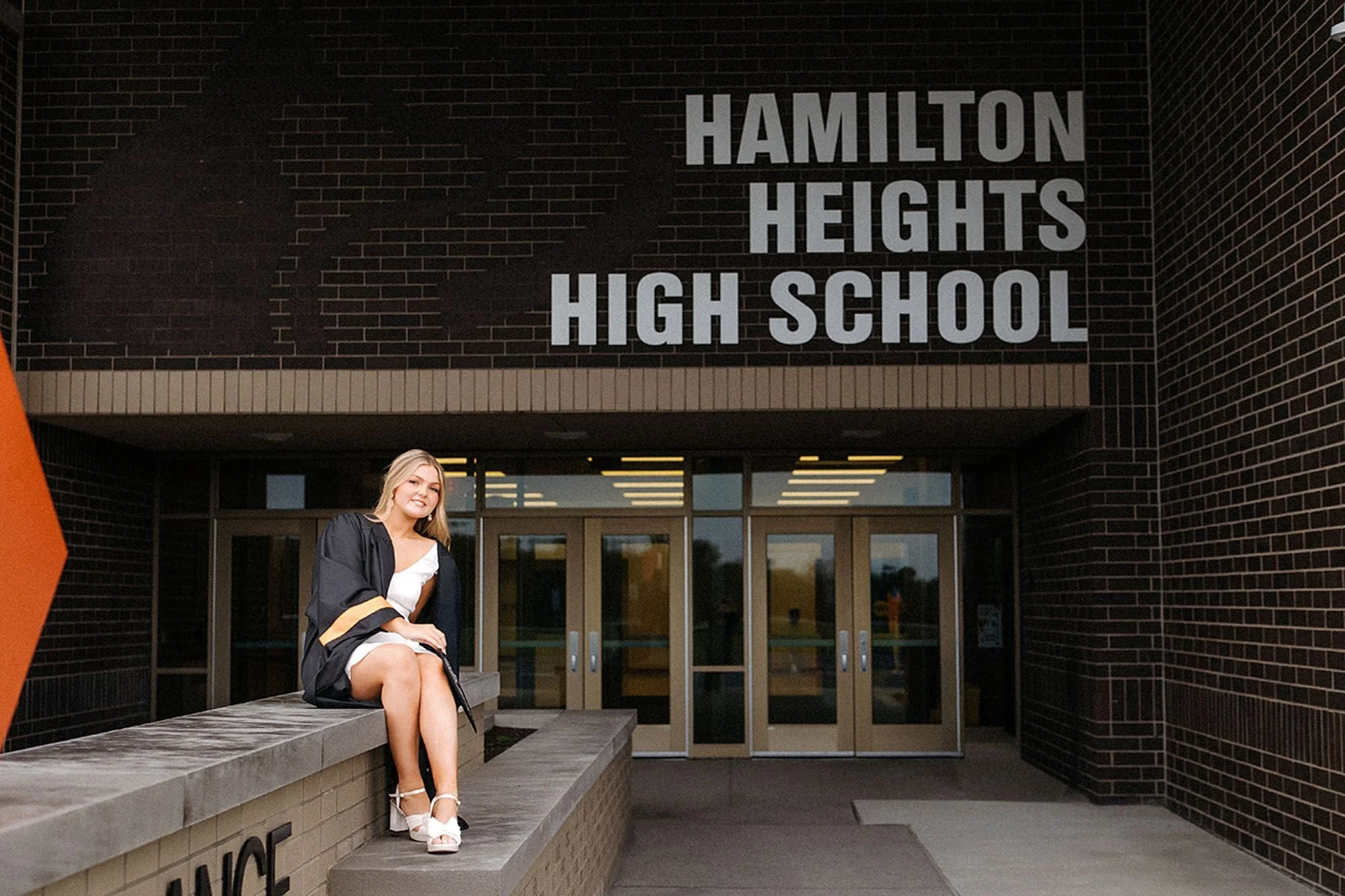 Hamilton Heights senior photos featuring a graduating high school senior in a cap and gown posing confidently outside Hamilton Heights High School