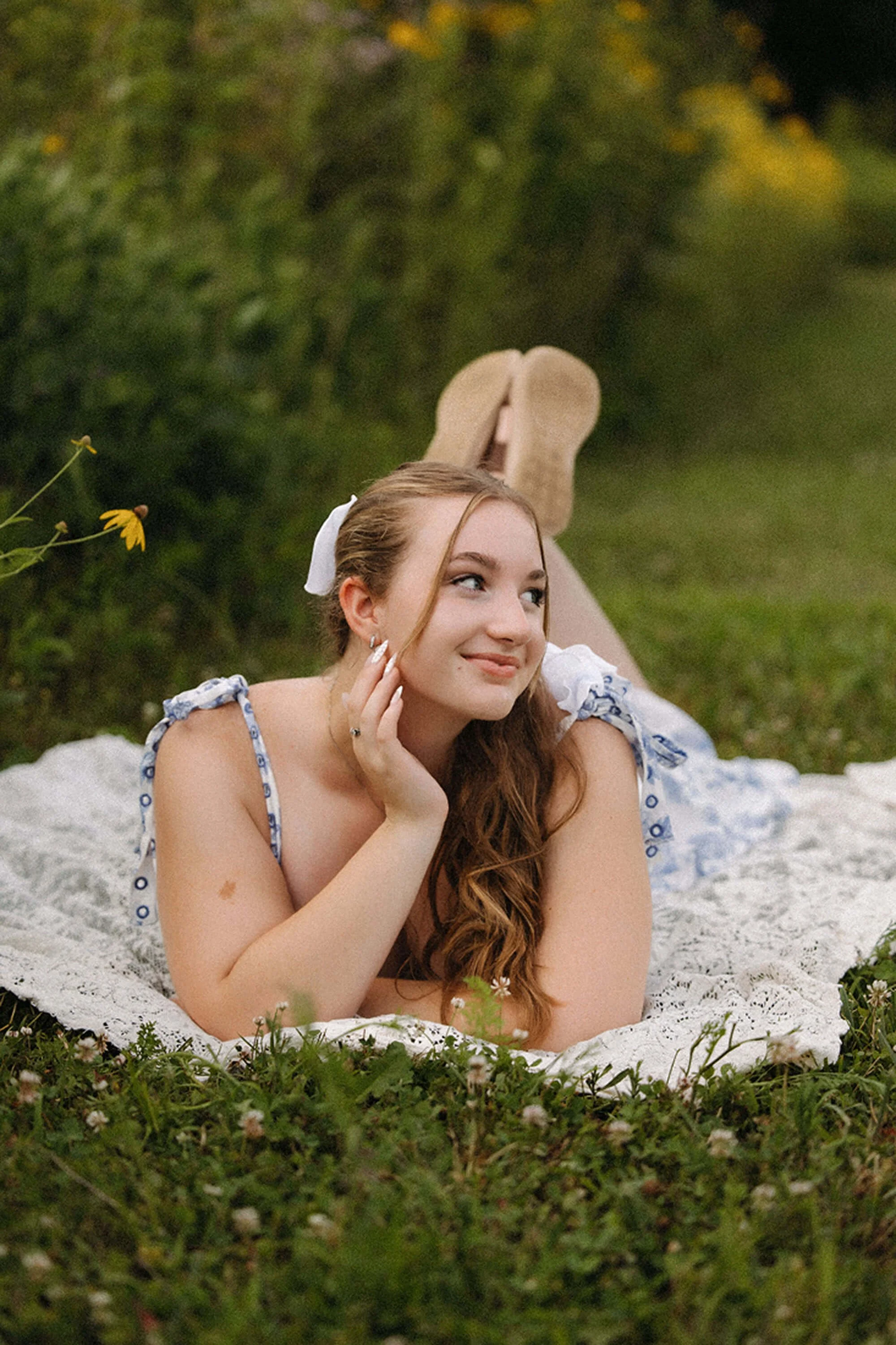 A senior girl relaxing on a blanket in a wildflower field, creating a soft and natural look for her  Senior Photos.