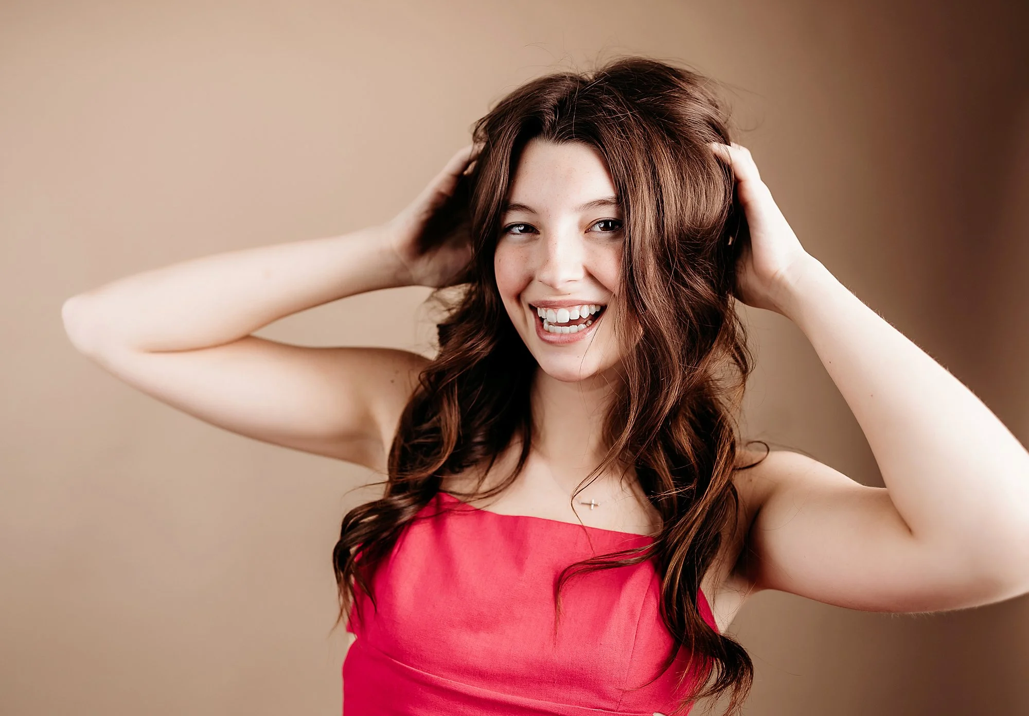 Modern studio senior portrait in Indianapolis featuring high school senior in pink dress against warm neutral backdrop