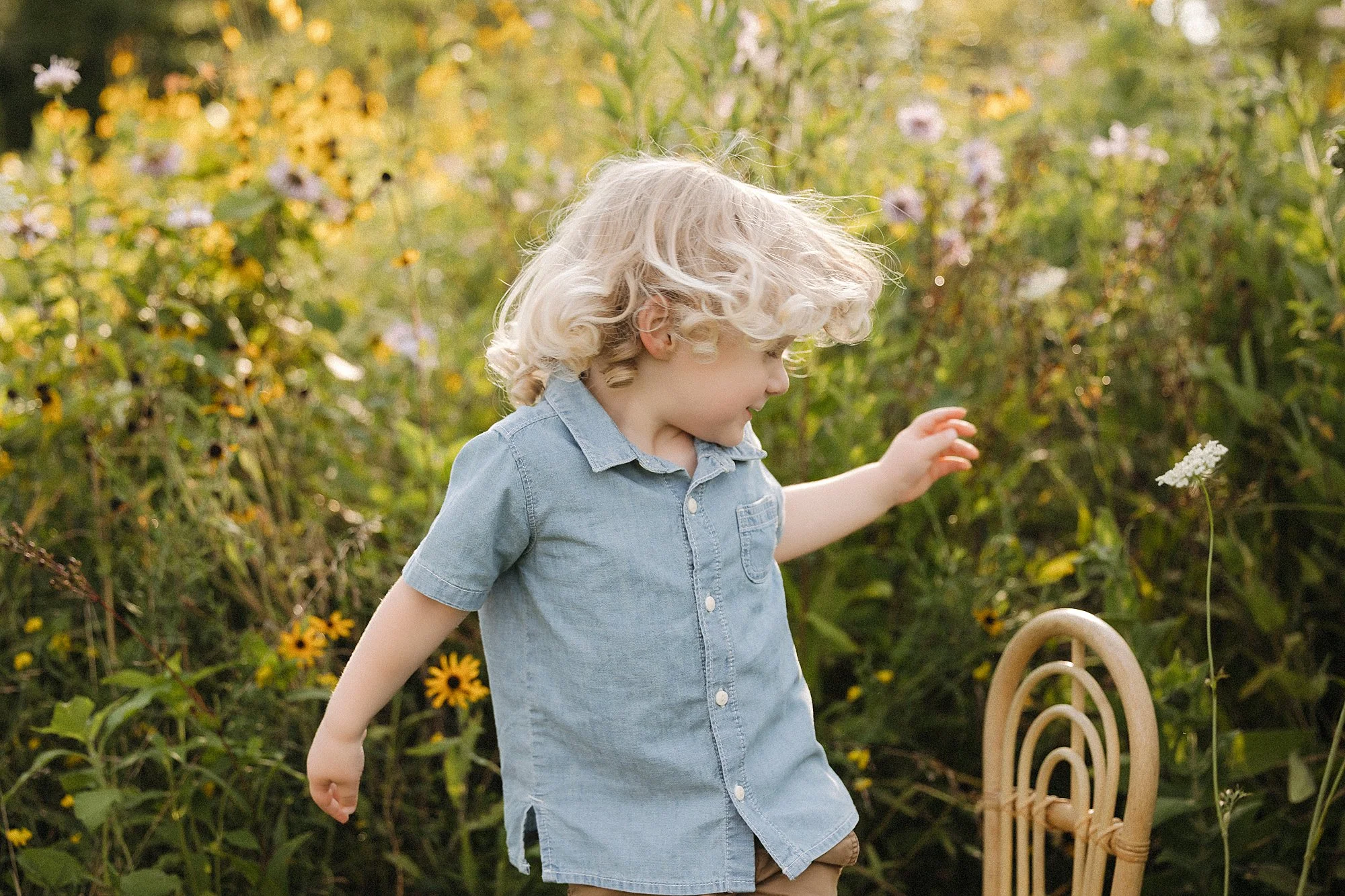 A young child in a blue shirt poses in a field, part of a Mini Session photography event