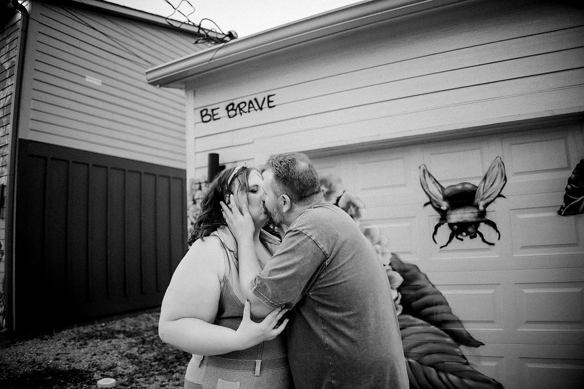  black and white portrait of husband kissing wife at one of the most unique photo locations in indianapolis, flower alley 