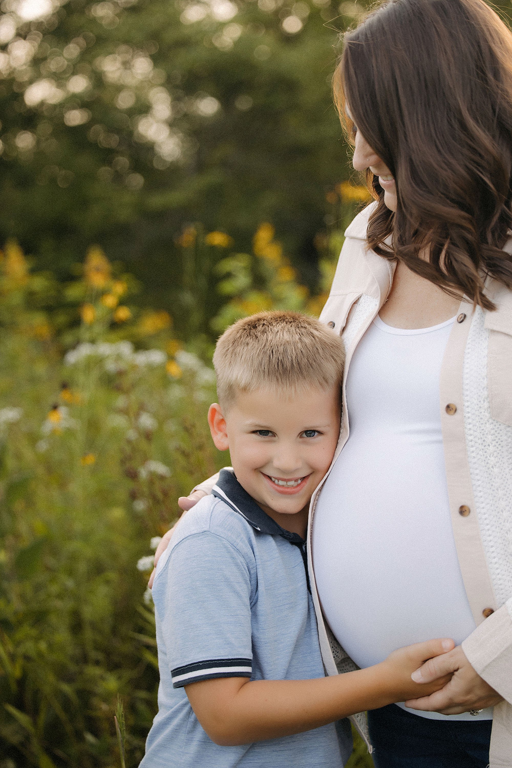 Young son hugging his pregnant mom during an outdoor maternity session in Westfield Indiana