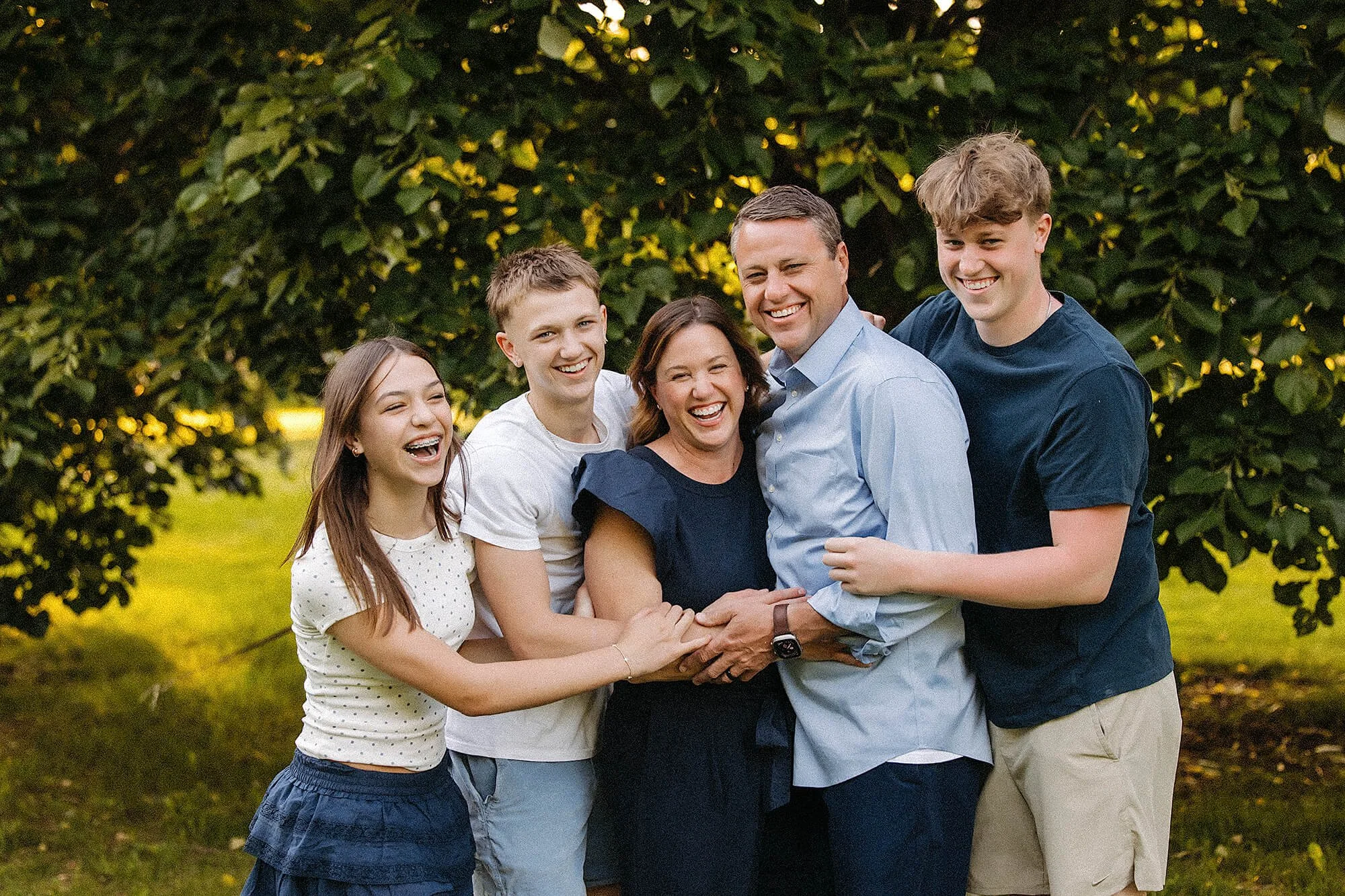 family with teens smiling together during a spring family mini session. by the heart narrative in holliday park