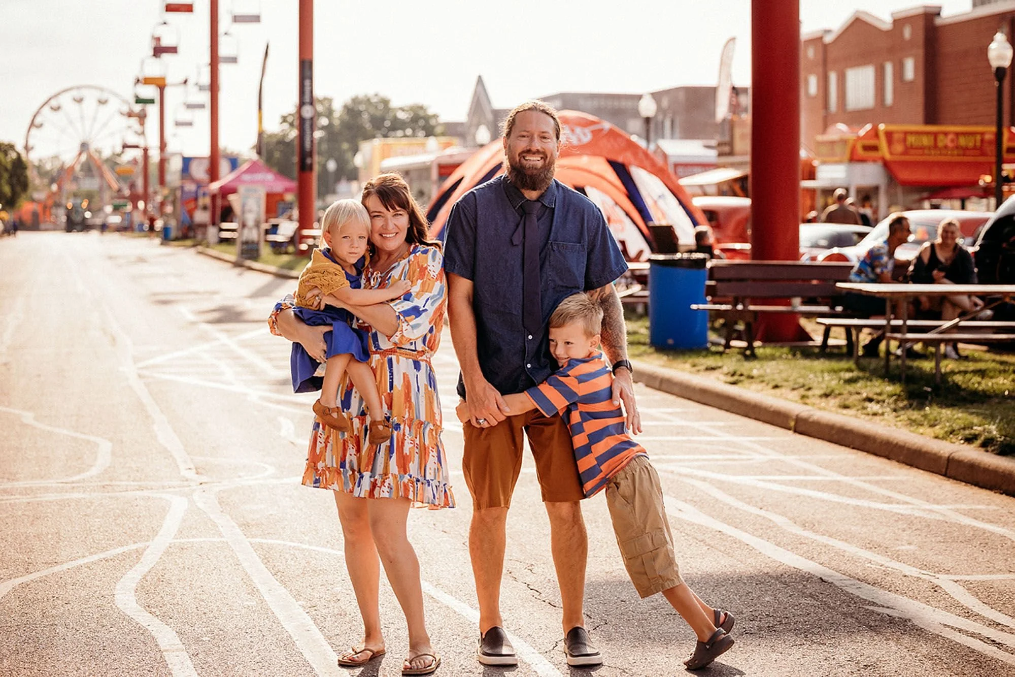 Family portrait at an Indiana fair with carnival lights in the background, capturing joyful Carnival Lights and Family Photos
