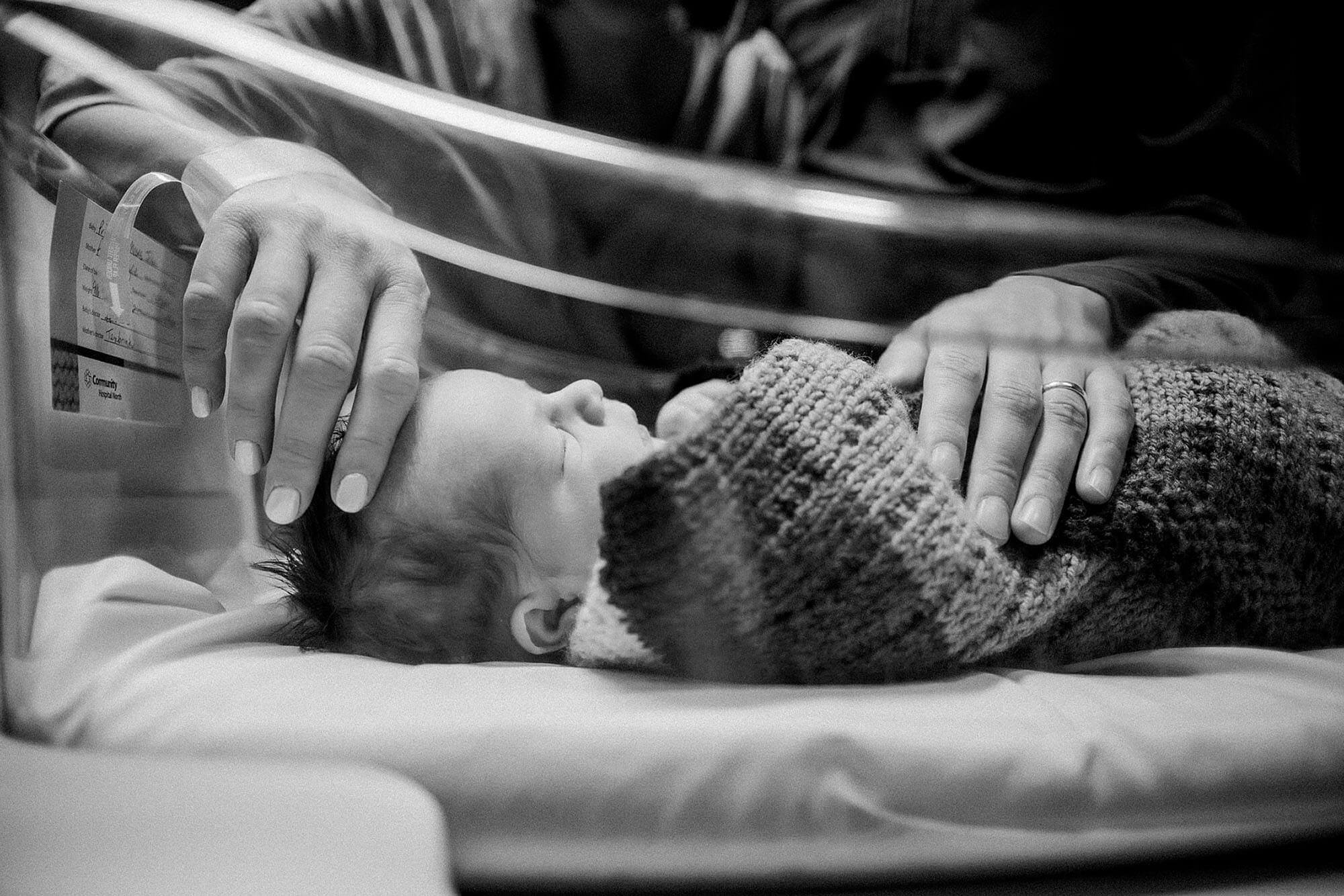 A black and white image of a baby in an incubator, captured during a Fresh 48 newborn hospital session