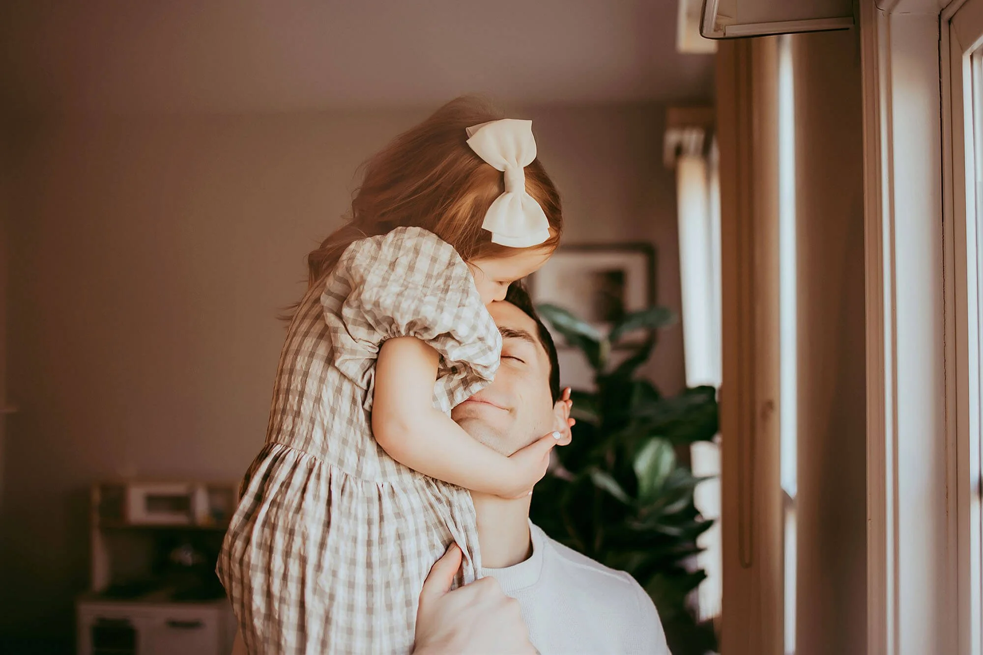 A man holds a young girl in his arms, capturing a sweet moment during a New Baby Photos session