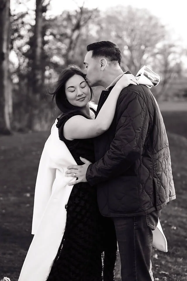 A timeless black-and-white take on Golden Hour Fall Pregnancy Announcement Photos, capturing an expecting couple embracing beneath the trees as they celebrate the little life growing between them.