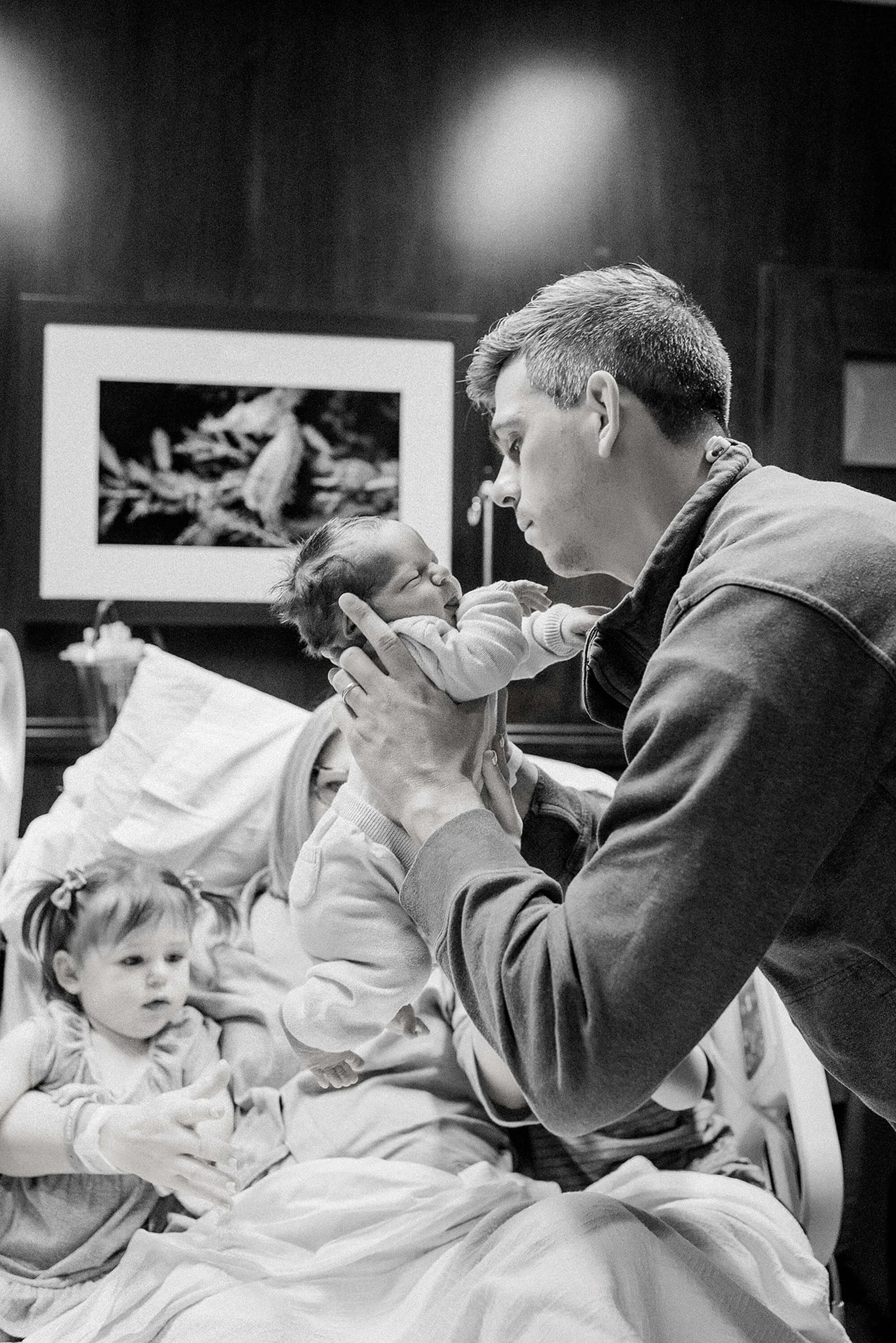 A father embraces his baby in a hospital, showcasing a heartfelt moment from a Fresh 48 session for newborn photography