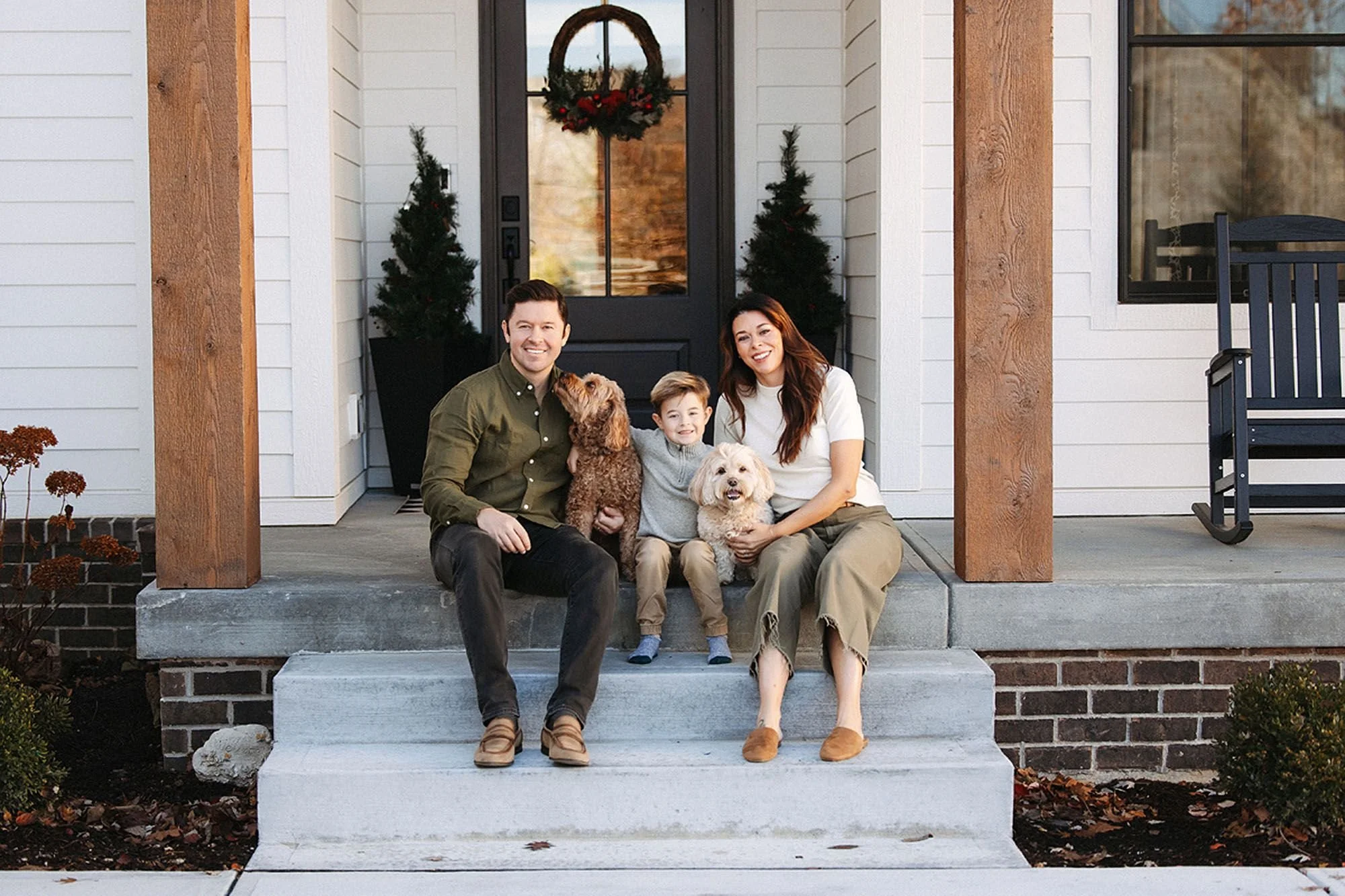 Family sitting on the front porch with their dogs during a cozy holiday session, capturing the warmth, love, and festive spirit of the Christmas holiday season