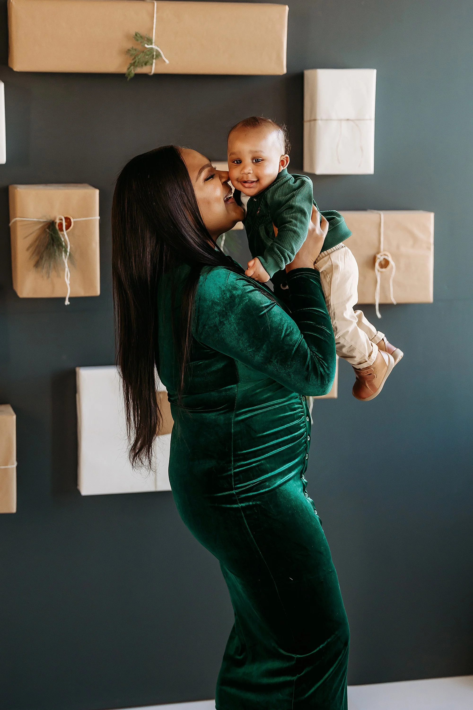 A mother in green velvet cradles her baby, captured during a Mini Session