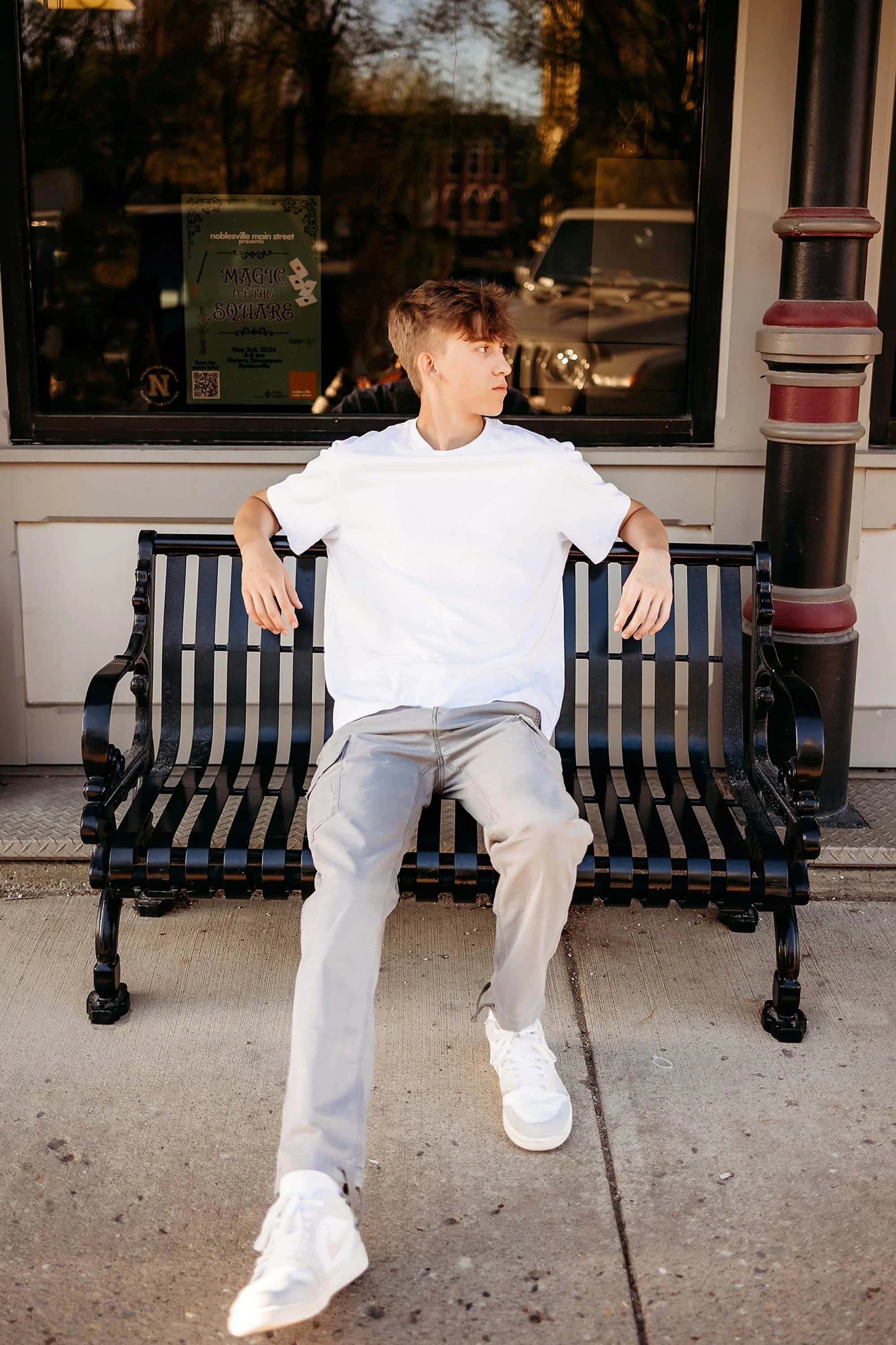 Downtown Noblesville scene featuring a man on a bench, wearing white sneakers for his downtown noblesville senior photo session