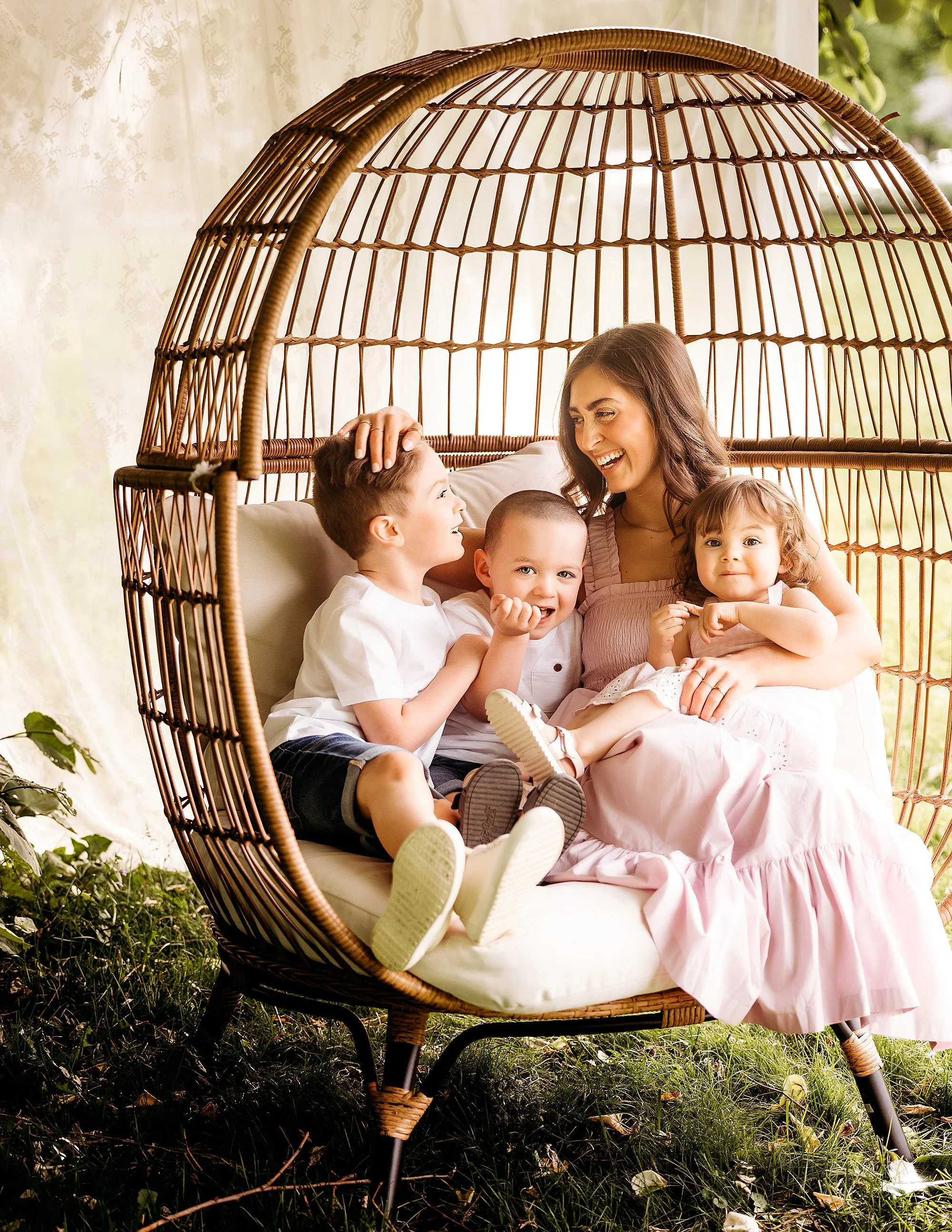 A woman and two children pose in a wicker chair, part of a Mini Session photography experience