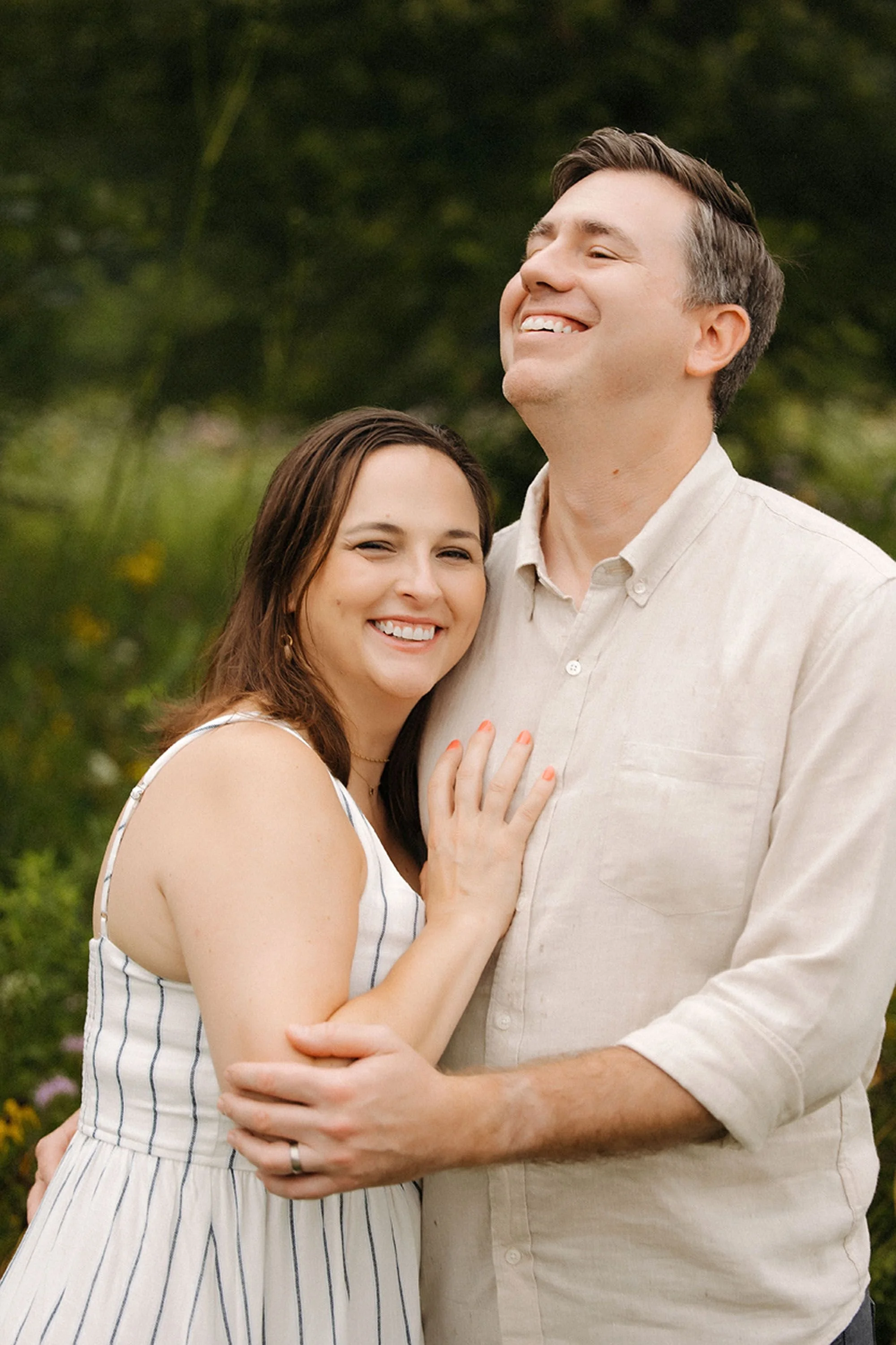 A couple laughing together outdoors during a summer extended family photo session in Westfield, Indiana.