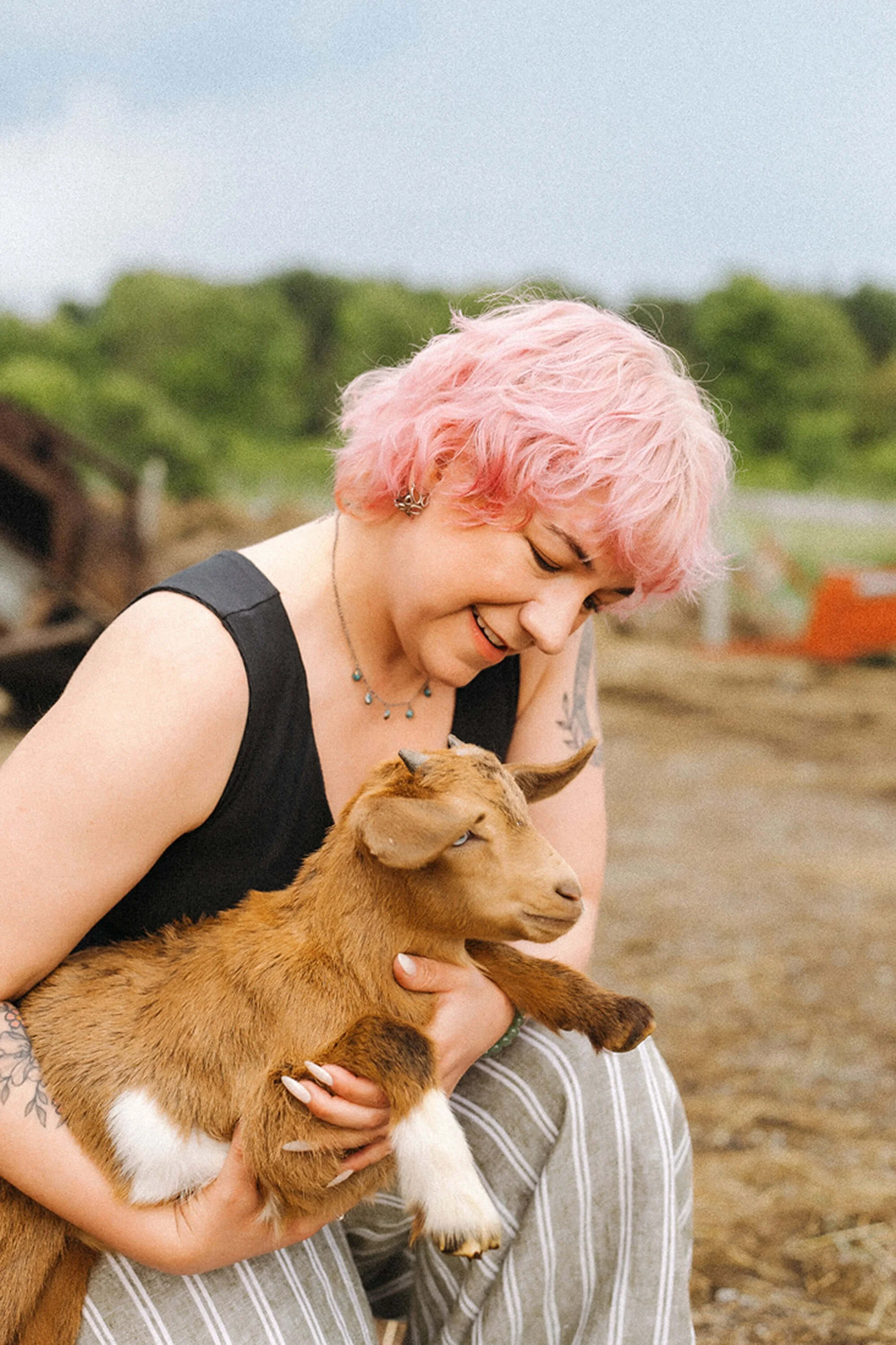 Person cuddling a playful baby goat during a visit to Heavenly Acres Farm