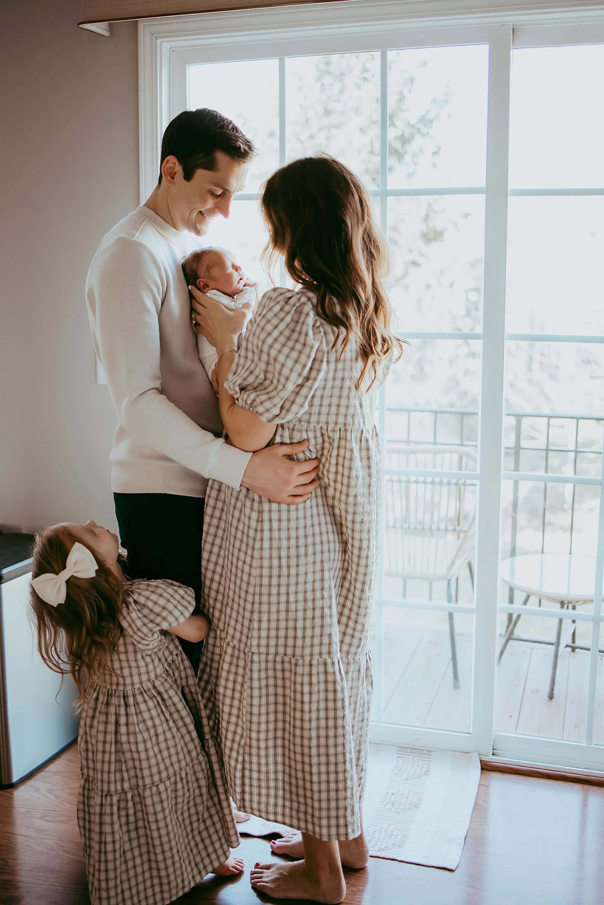 Family gathered in the living room for a new baby photo session, smiling and enjoying the moment together