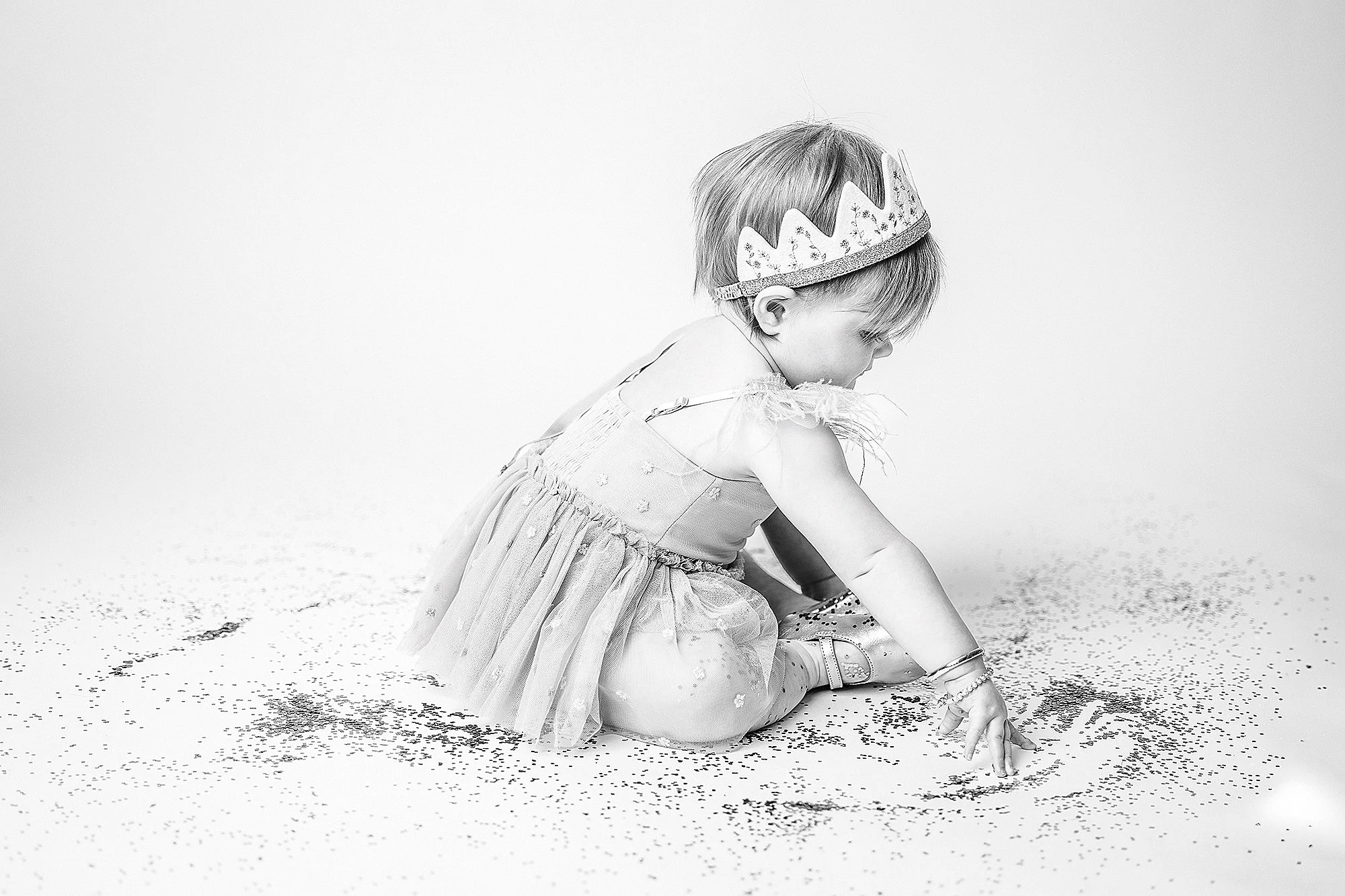 studio milestone photo of toddler playing with glitter