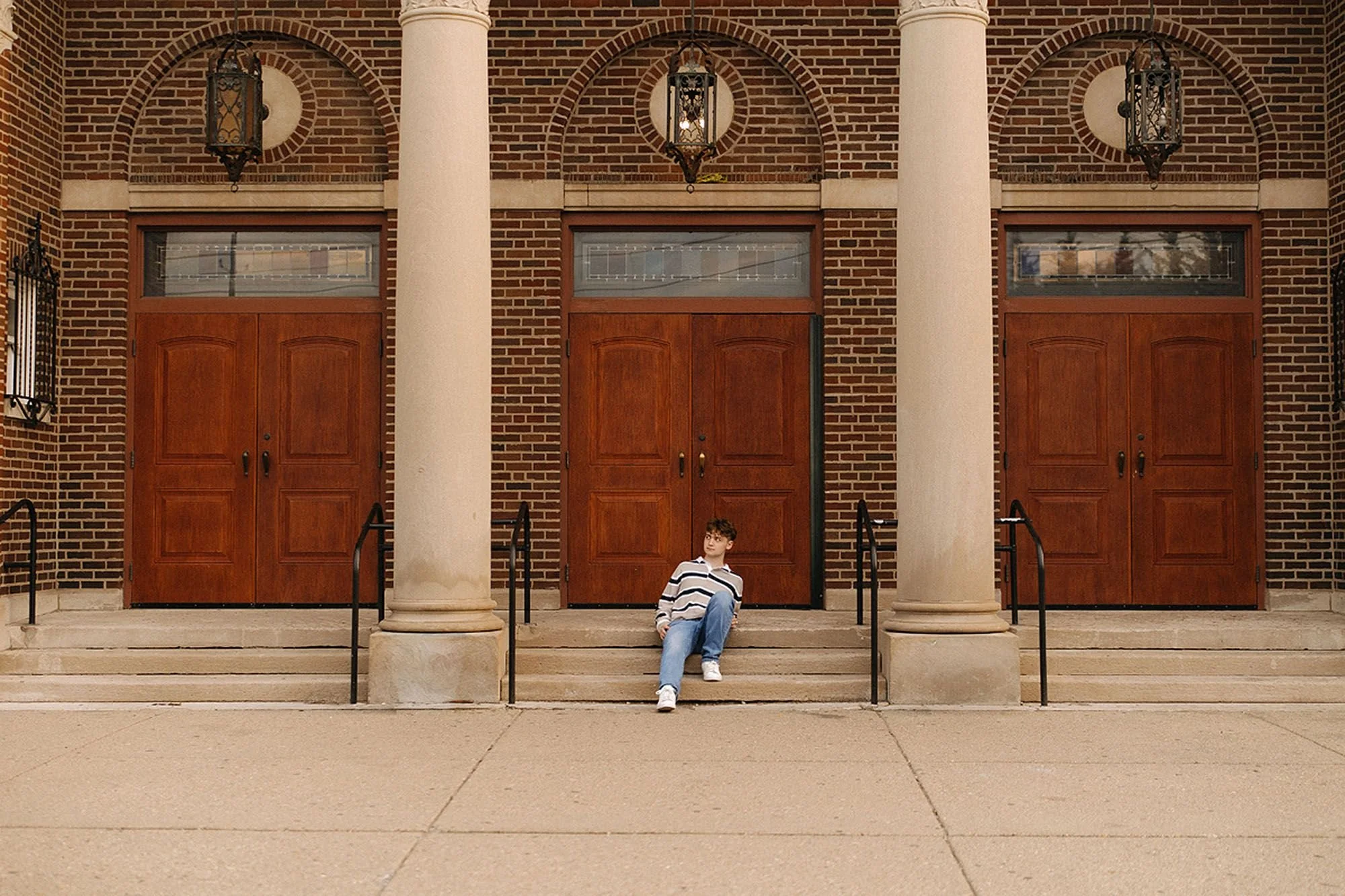 A young adult poses for senior photos on the steps of a church in Fountain Square, Indianapolis, surrounded by historic architecture
