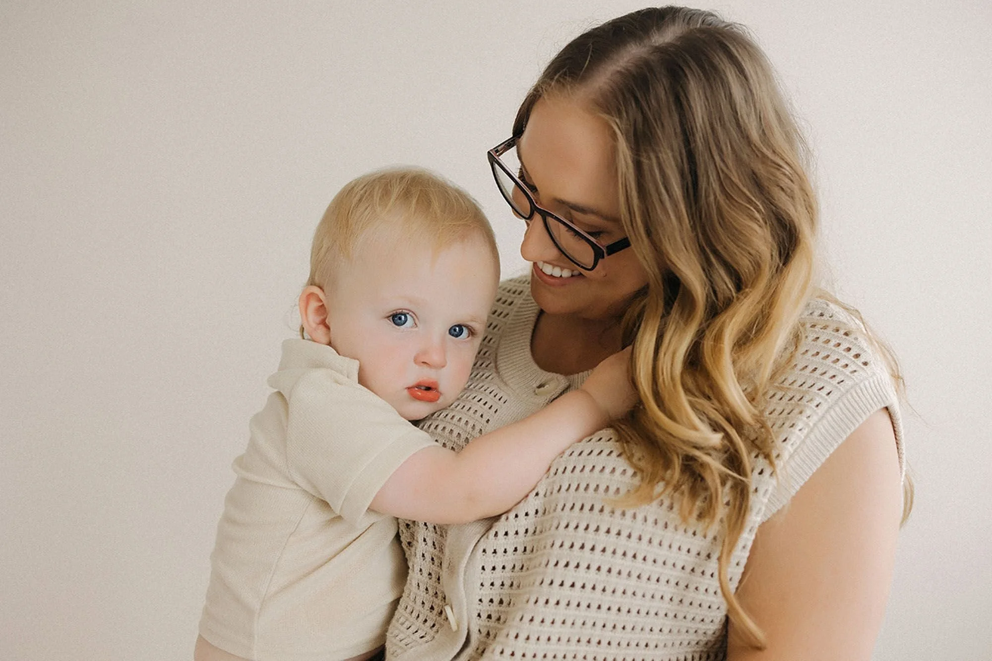 Heartwarming studio family photo of a mother cuddling her baby during a cozy portrait session.
