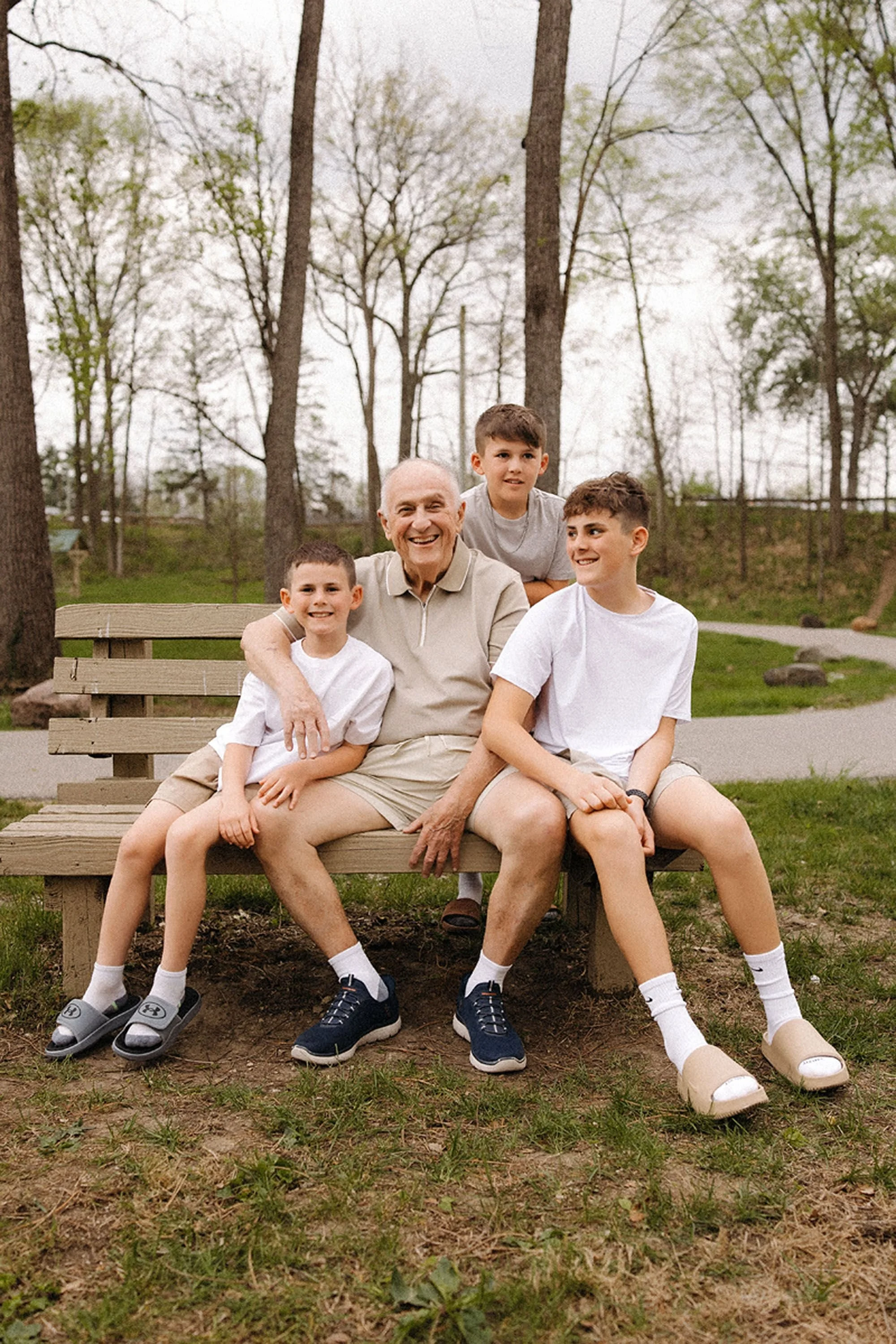Grandfather sitting with his three grandsons on a park bench, showing how to prepare kids for family photos with love, comfort, and genuine smiles