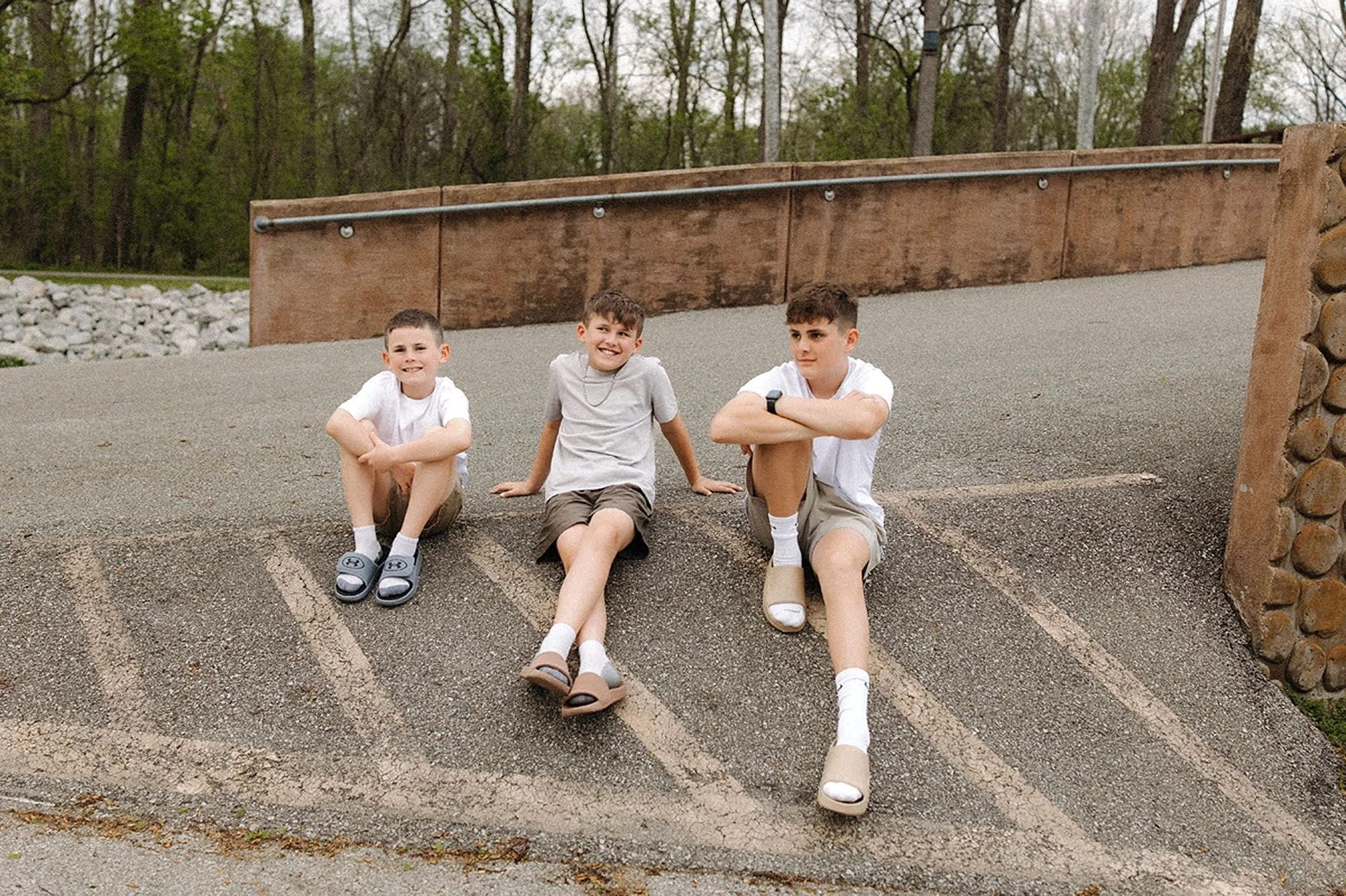 Three brothers sitting together outdoors before a family photo session, showing how to prepare kids for family photos with a fun and relaxed approach