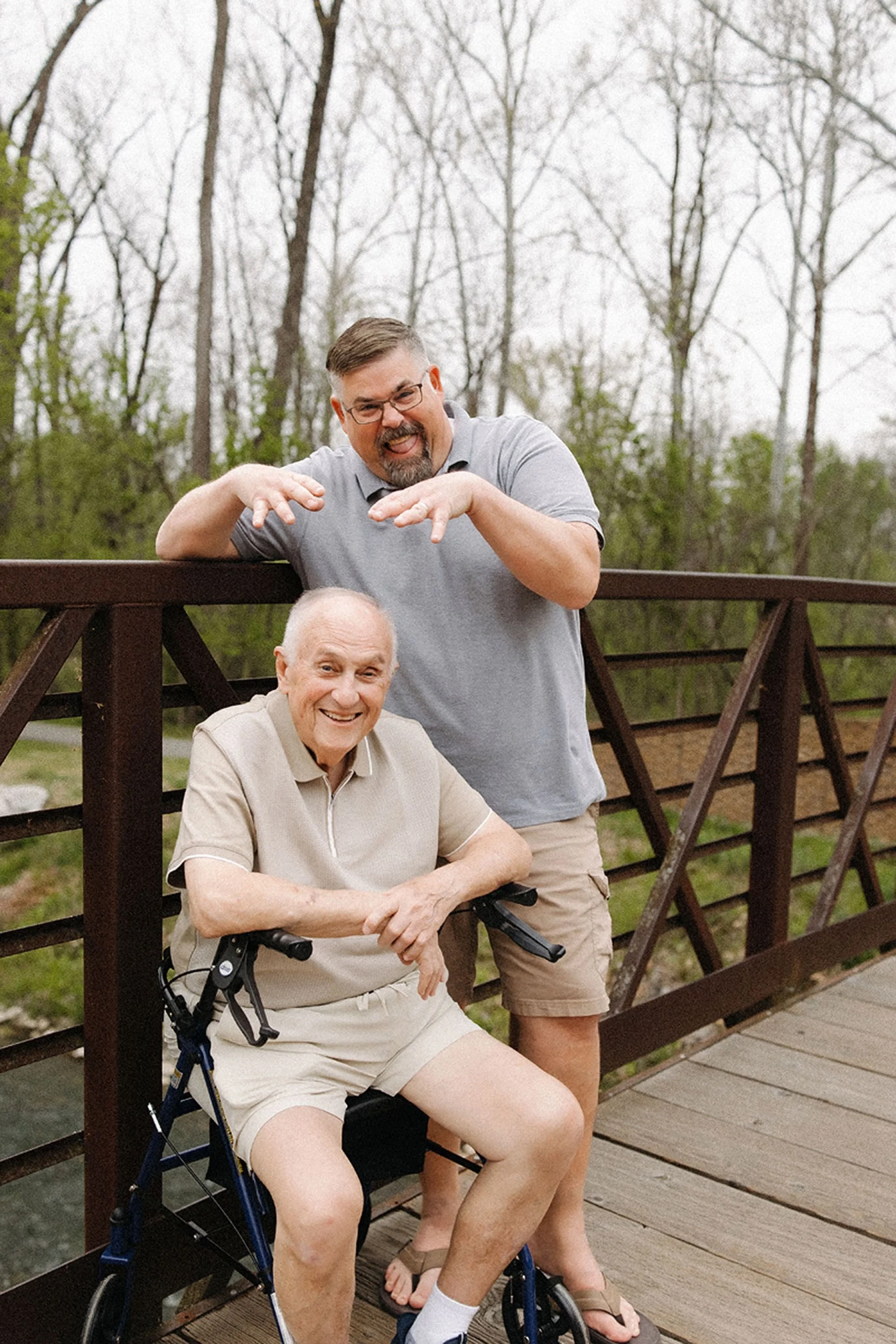 Father and grandfather sharing a playful moment on a bridge, showing how a fun and relaxed attitude helps prepare kids for family photos.