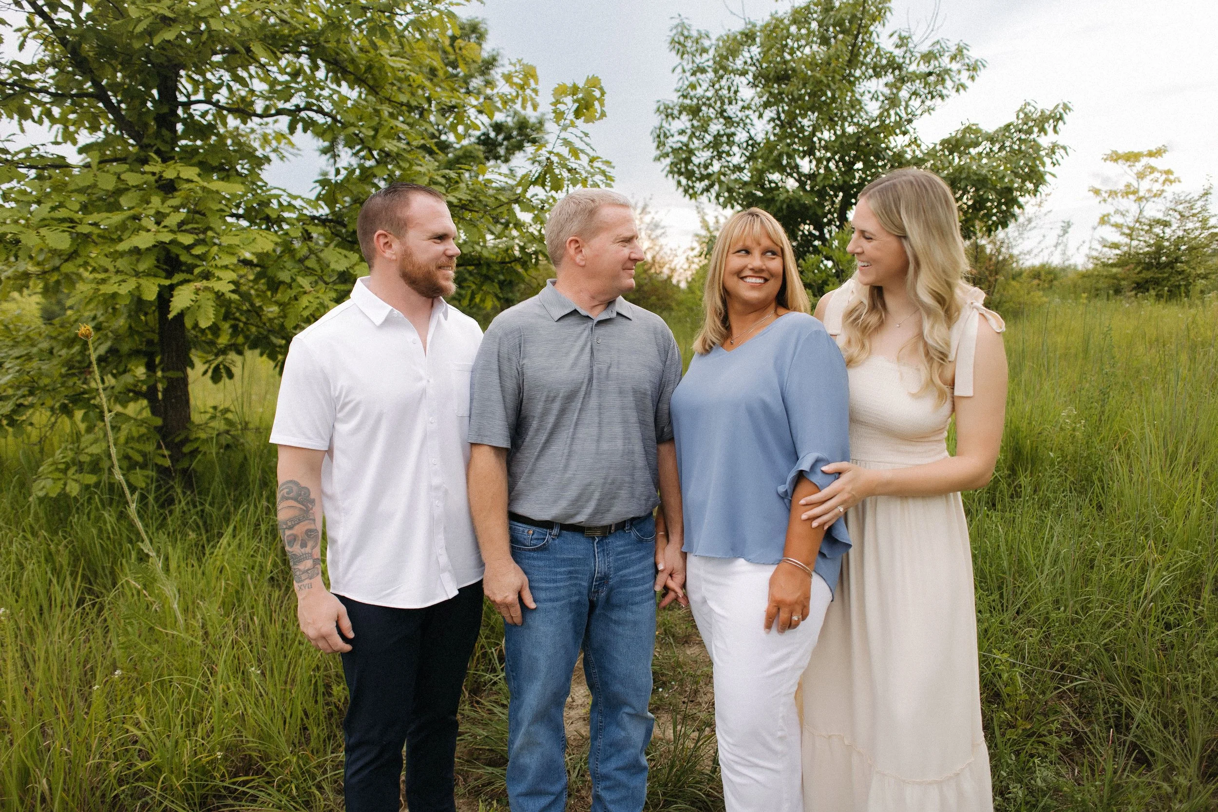 An extended family poses happily in a sunny field, capturing a joyful moment together in a photograph