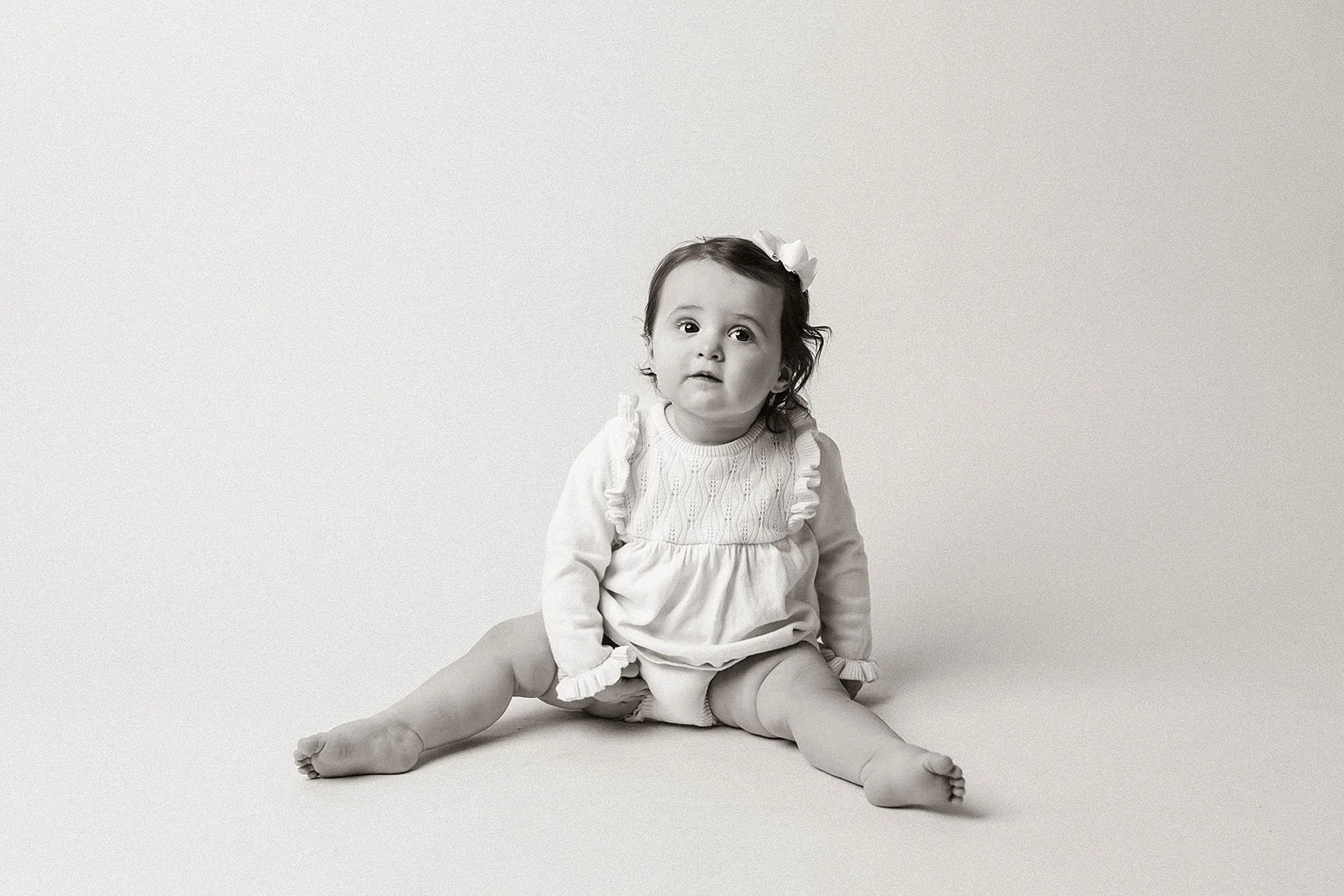 A baby seated on the floor, marking their first birthday milestone in a photography session in Westfield, Indiana