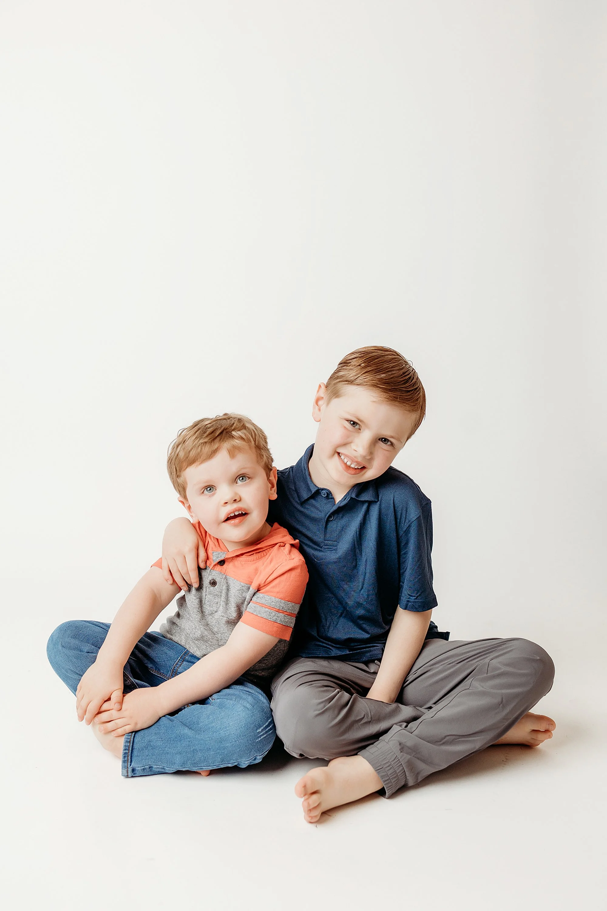 Siblings sharing a playful moment during a relaxed personality portrait session in a studio setting