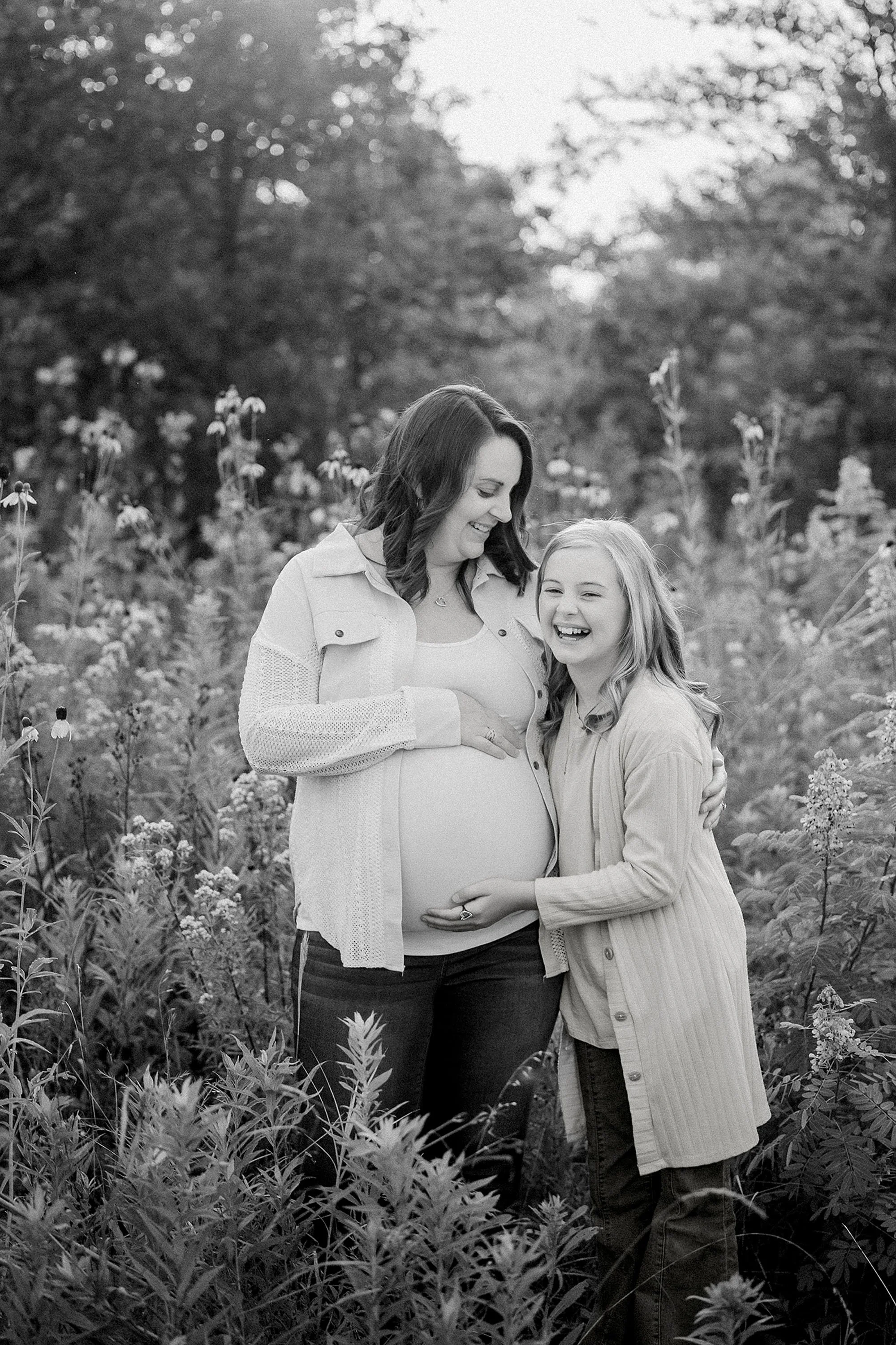Black and white maternity photo of a pregnant mom surrounded by her two children in a field of wildflowers
