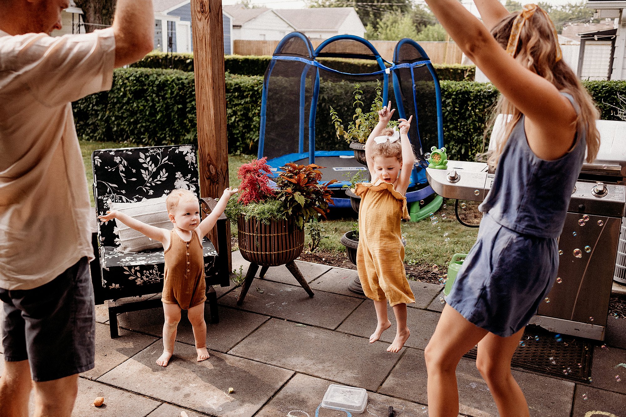 A joyful family enjoys a backyard photography session in Indianapolis, Indiana, surrounded by greenery and smiles