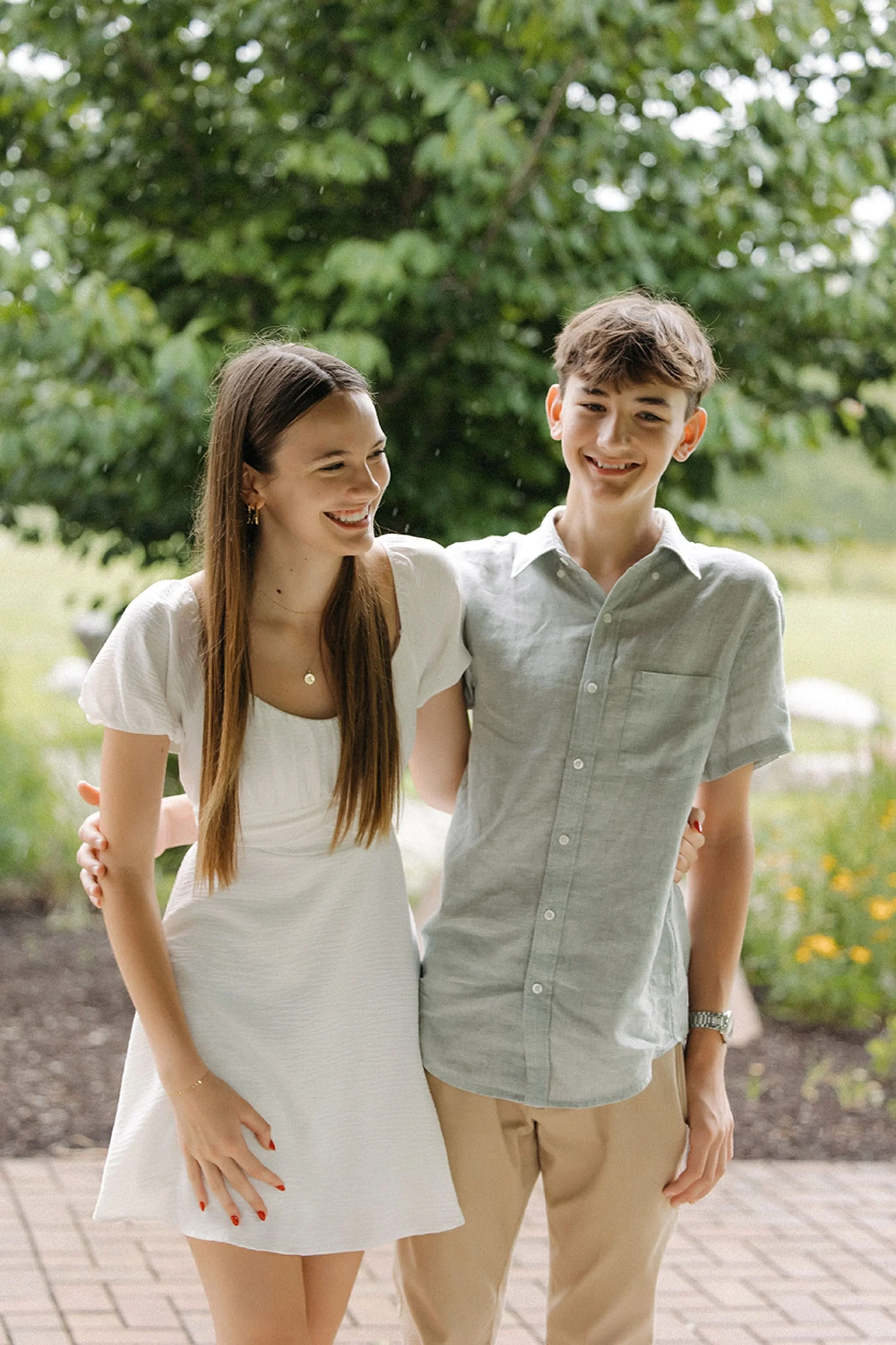 Teenage siblings standing close together and smiling during a summer family photo session.