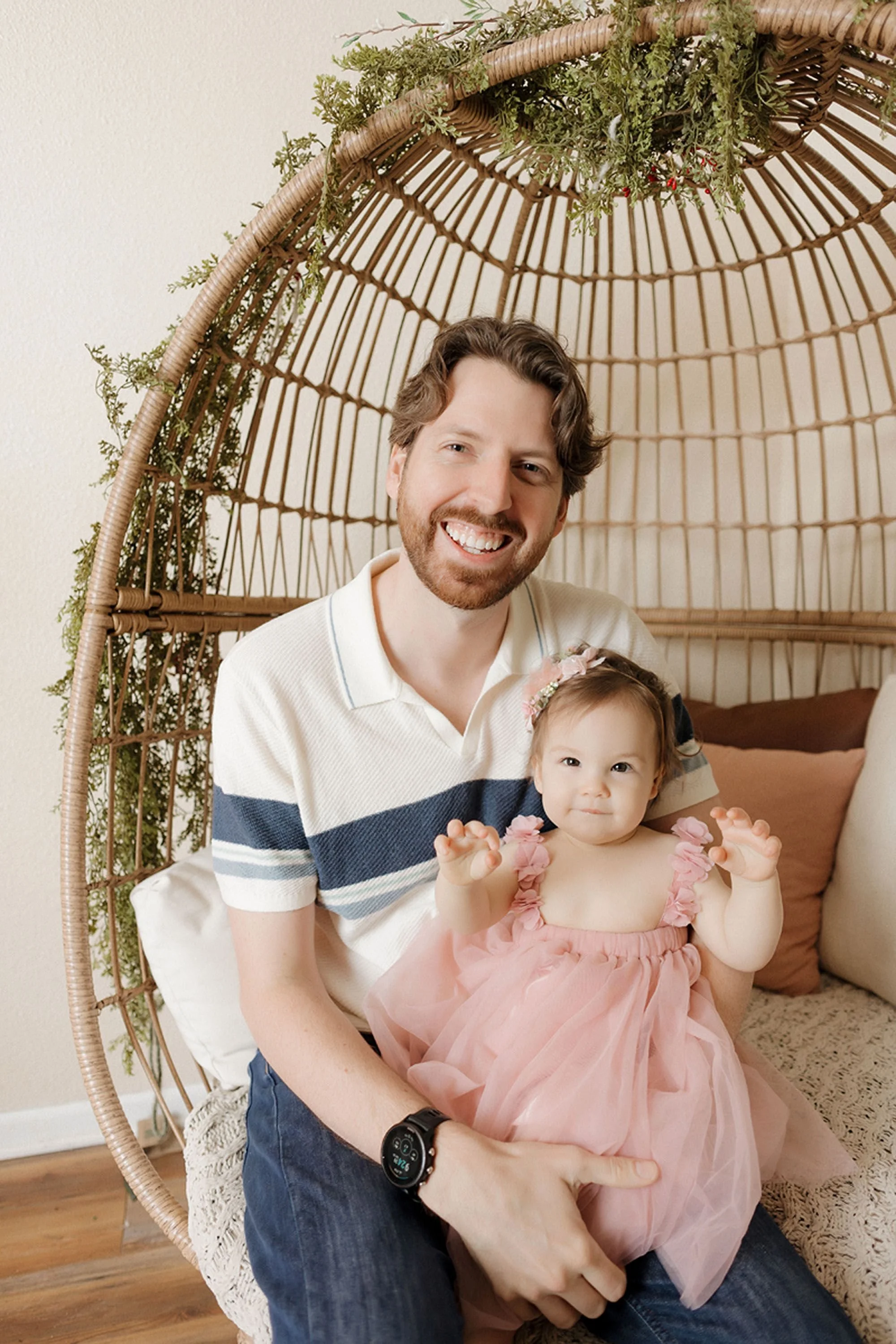 Father and daughter sharing a sweet moment during Groovy One cake smash photos in Indianapolis with a blush pink dress and cozy boho studio setting