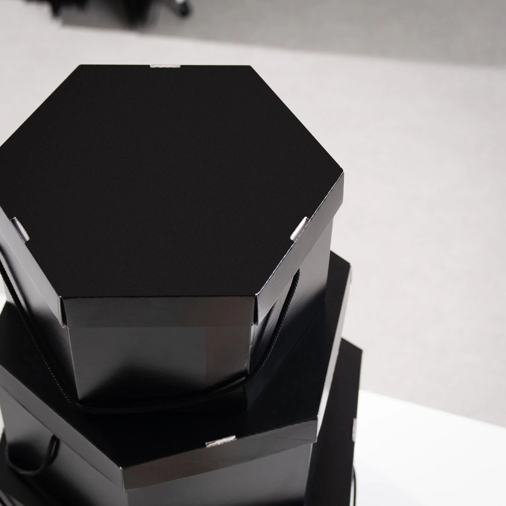 Stacked black hat boxes against a light grey and white background.