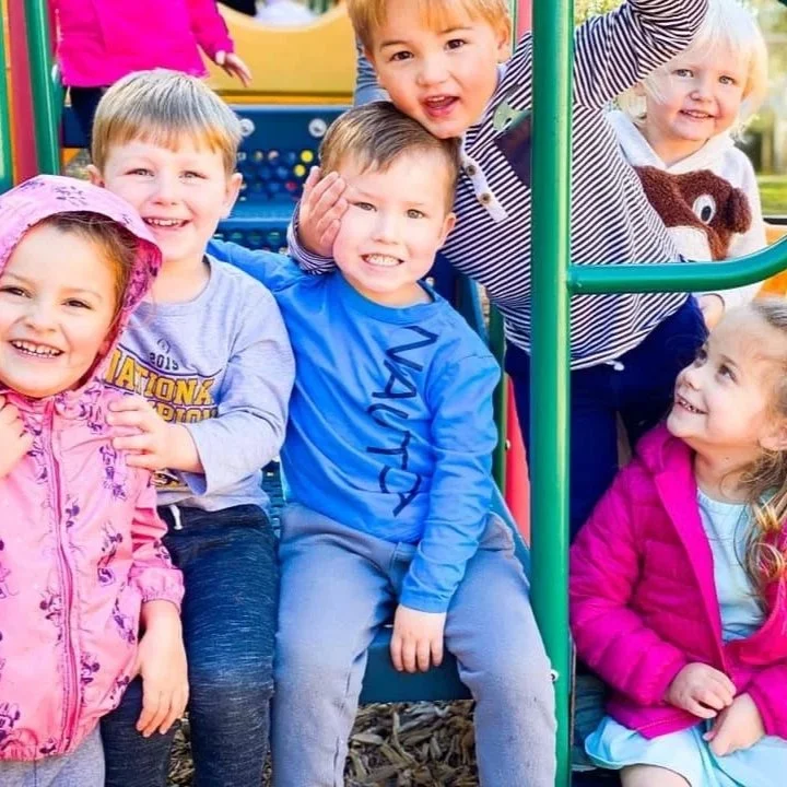 Group of six children smiling and playing on a playground