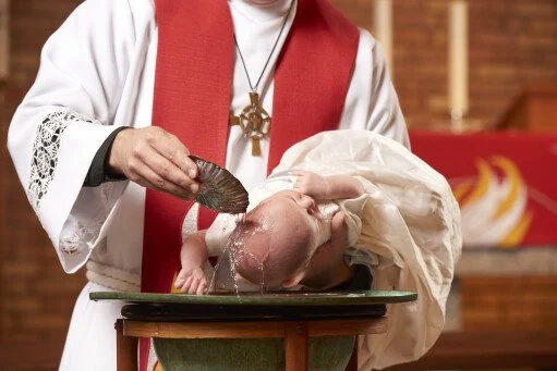 A priest performing a baptism ceremony on a baby in a church.