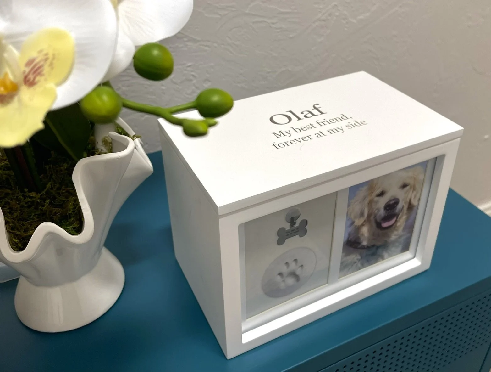 picture of custom white urn with engraving on top of a blue table at Comforting Currents Water-based Crematory
