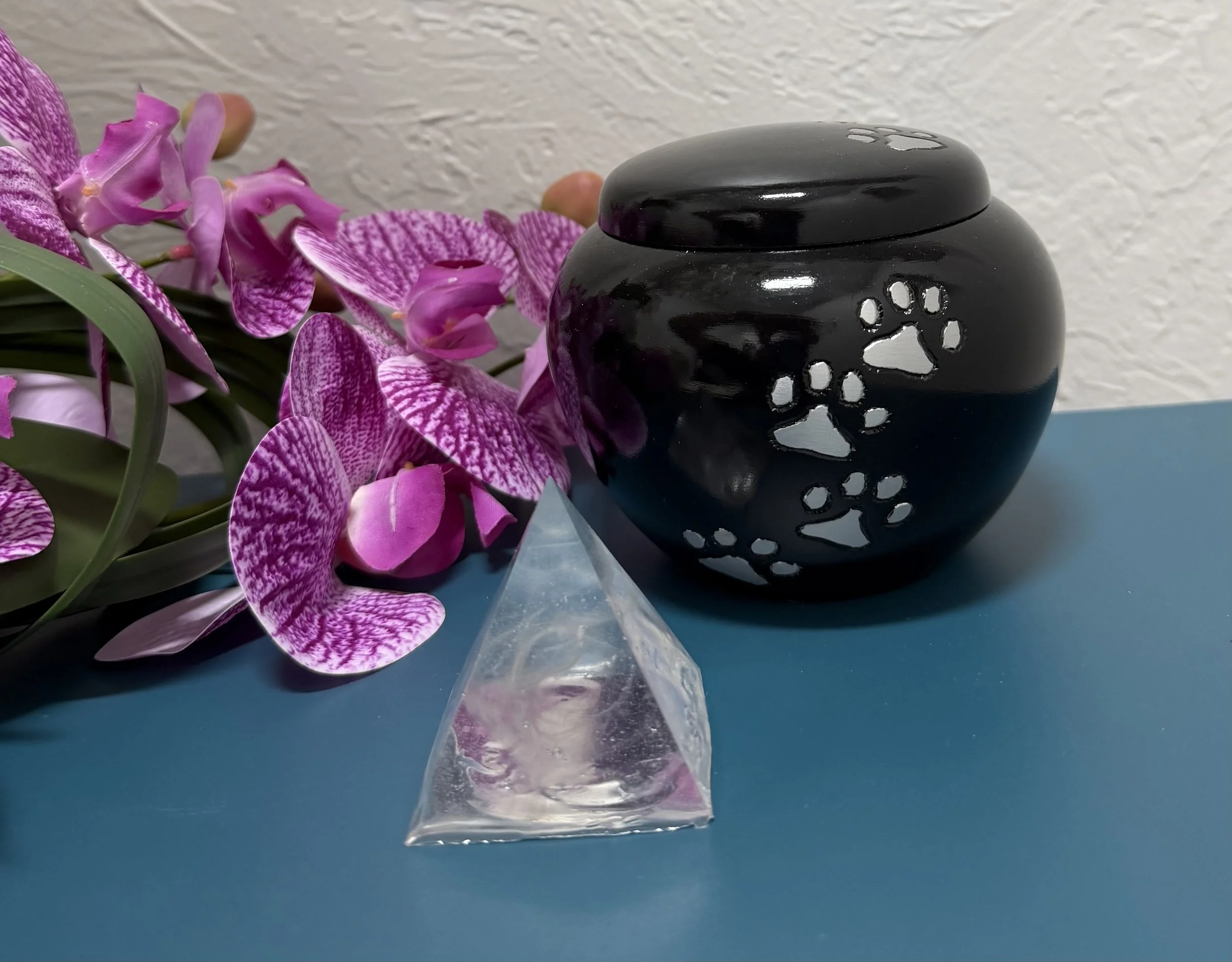 Ceramic urn with pawprints and a delicate fur clipping within a resin pyramid