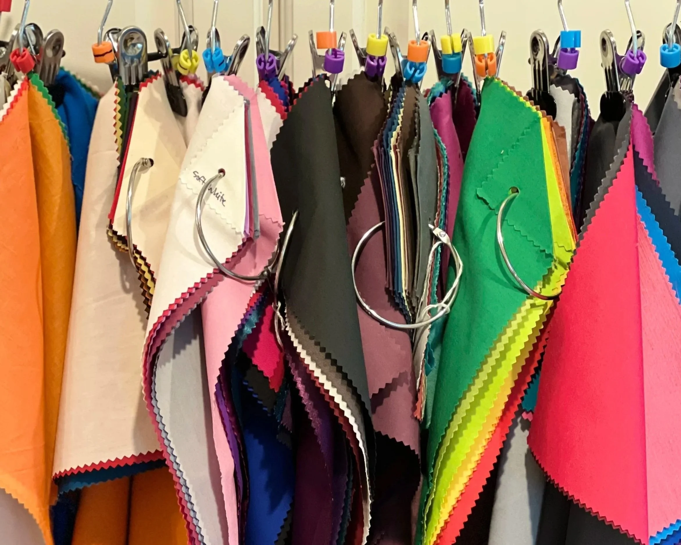 A variety of fabric swatches in different colors hanging on hooks in a display.