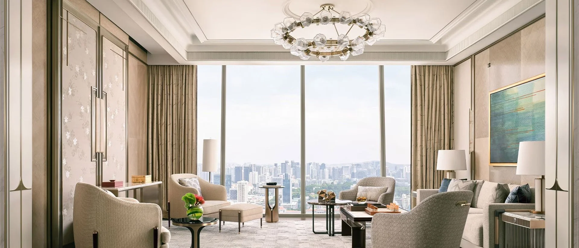 Luxurious living room with large floor-to-ceiling windows showing a city skyline, neutral-toned furniture, a modern chandelier, and art on the walls.