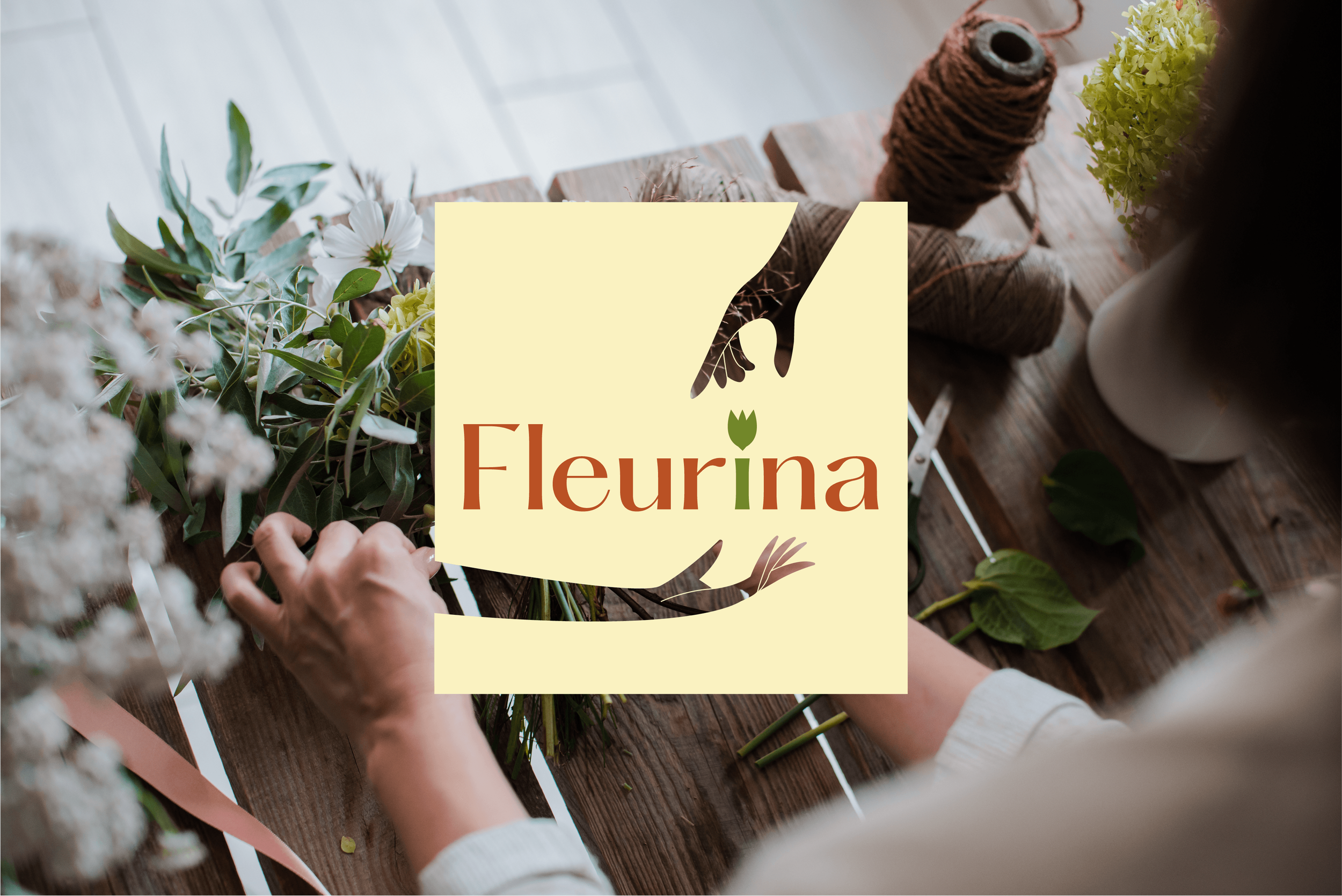Un artisan floriste arrangeant des fleurs et des feuillages sur une table en bois avec un logo "Fleurina" sur la photo.