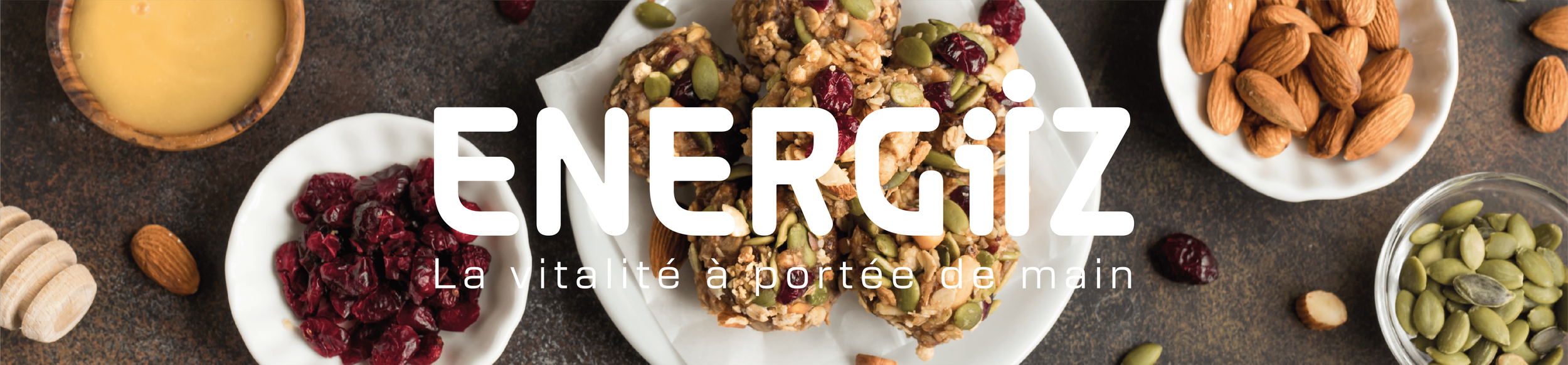 Plate de barres énergétiques aux graines, fruits secs et noix, avec des amandes, des graines de courge, un bol de miel, et d'autres noix et fruits secs autour.