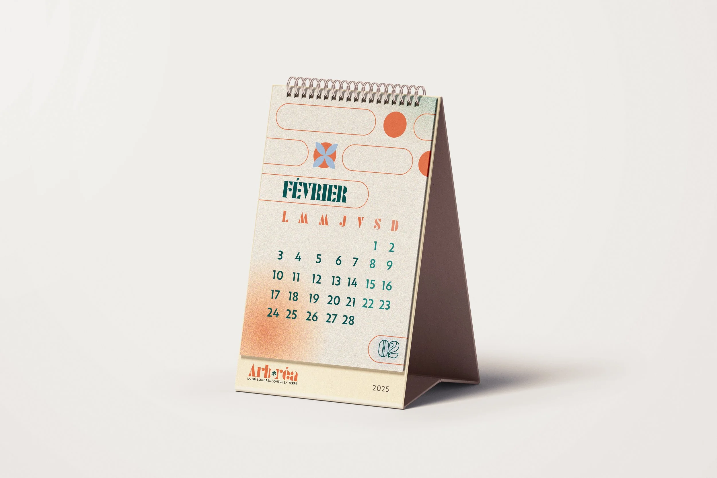 Un calendrier de bureau pour le mois de février 2025, avec un design coloré et moderne, posé sur une surface blanche, avec une couverture beige et des détails graphiques en bleu et rouge.
