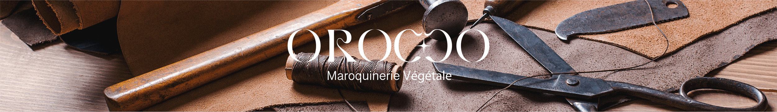 Outils de maroquinerie sur un plan en cuir et bois, incluant des morceaux de cuir, des ciseaux, des bobines de fil et d'autres outils pour la fabrication de maroquinerie végétale.