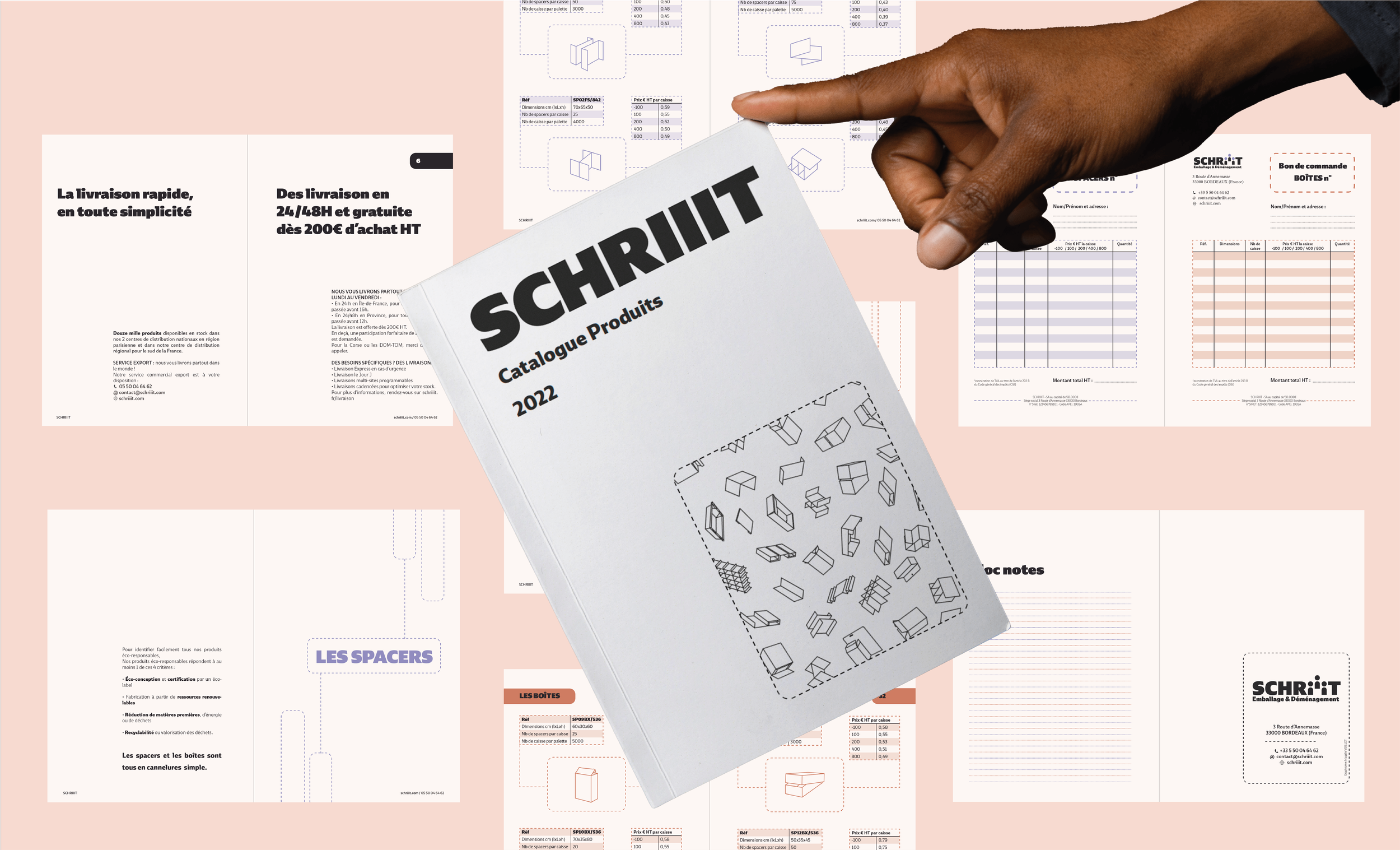 Une main tenant un catalogue de produits SCHIIIT, avec plusieurs documents techniques et fiches produits éparpillés sur une surface rose en arrière-plan.
